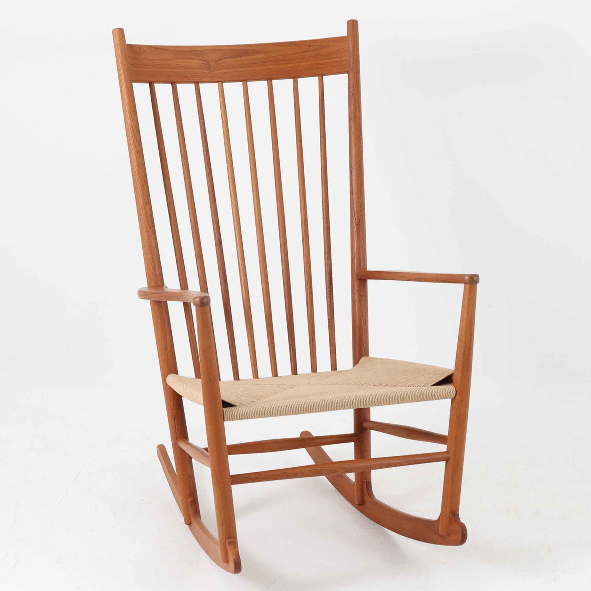 Hans J. Wegner（ハンス・J・ウェグナー）がデザインし、FDB Mobler社が製造したロッキングチェア「J16」。美しいチーク材のフレームとペーパーコードの座面が融合した、北欧ビンテージ家具を代表する一脚です。ハイバックと広めのアームが包み込むような座り心地を生み、ロッキングの揺れが心地よい安らぎをもたらします。経年により深みを増したチーク材の風合いが空間に静かな存在感を添え、読書やリラックスタイムに最適です。チーク材のモデルは希少で、現地デンマークのオークションで入手した確かな逸品です。