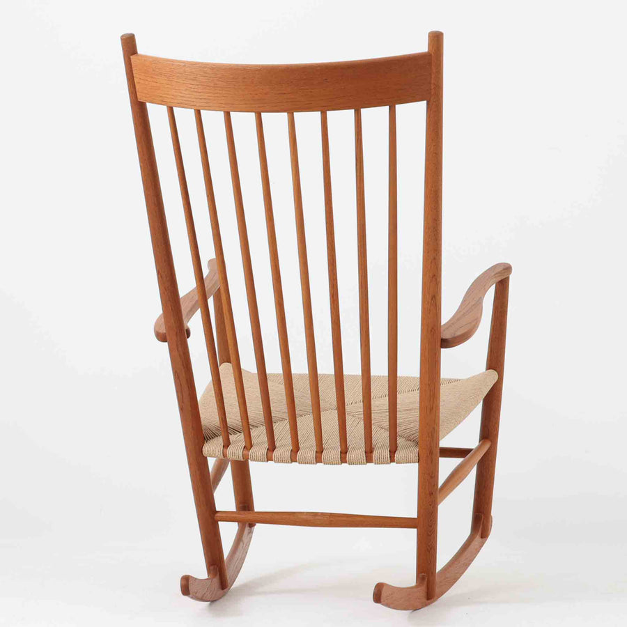 Hans J. Wegner（ハンス・J・ウェグナー）がデザインし、FDB Mobler社が製造したロッキングチェア「J16」。美しいチーク材のフレームとペーパーコードの座面が融合した、北欧ビンテージ家具を代表する一脚です。ハイバックと広めのアームが包み込むような座り心地を生み、ロッキングの揺れが心地よい安らぎをもたらします。経年により深みを増したチーク材の風合いが空間に静かな存在感を添え、読書やリラックスタイムに最適です。チーク材のモデルは希少で、現地デンマークのオークションで入手した確かな逸品です。