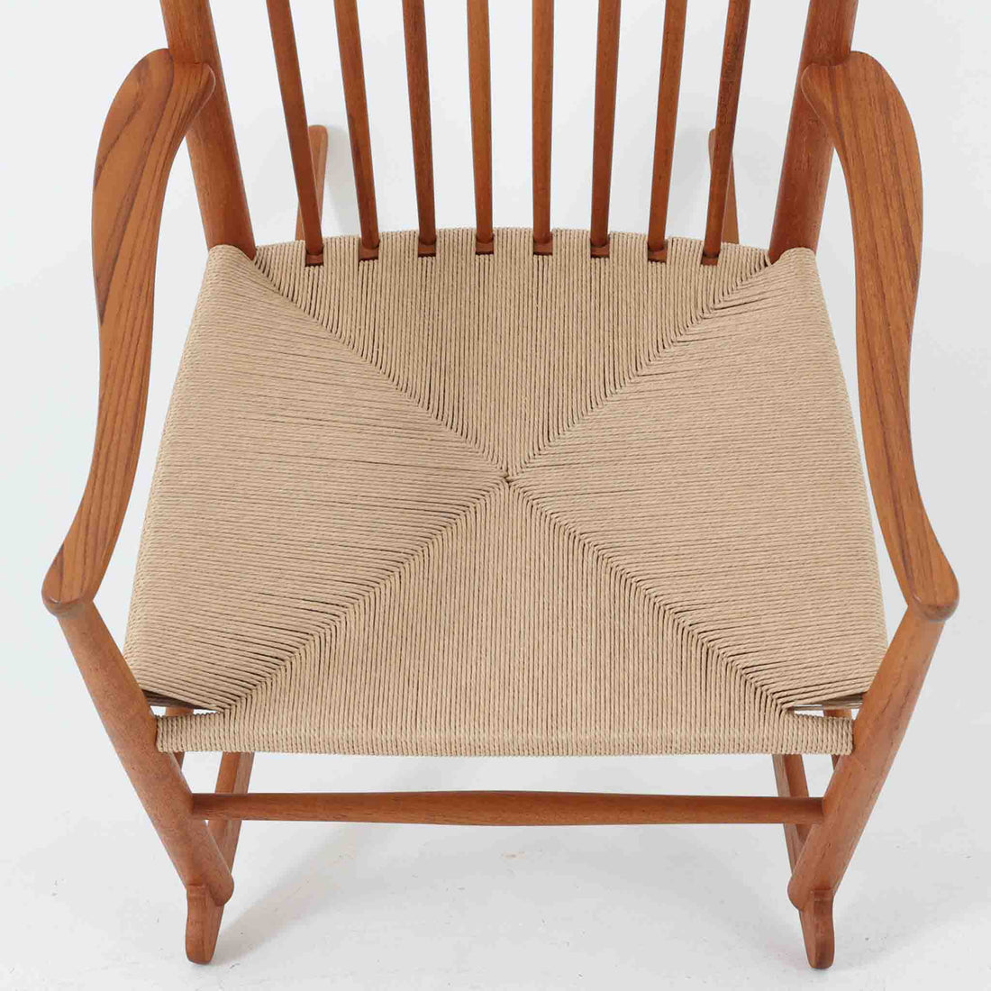 Hans J. Wegner（ハンス・J・ウェグナー）がデザインし、FDB Mobler社が製造したロッキングチェア「J16」。美しいチーク材のフレームとペーパーコードの座面が融合した、北欧ビンテージ家具を代表する一脚です。ハイバックと広めのアームが包み込むような座り心地を生み、ロッキングの揺れが心地よい安らぎをもたらします。経年により深みを増したチーク材の風合いが空間に静かな存在感を添え、読書やリラックスタイムに最適です。チーク材のモデルは希少で、現地デンマークのオークションで入手した確かな逸品です。