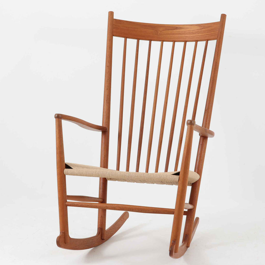 Hans J. Wegner（ハンス・J・ウェグナー）がデザインし、FDB Mobler社が製造したロッキングチェア「J16」。美しいチーク材のフレームとペーパーコードの座面が融合した、北欧ビンテージ家具を代表する一脚です。ハイバックと広めのアームが包み込むような座り心地を生み、ロッキングの揺れが心地よい安らぎをもたらします。経年により深みを増したチーク材の風合いが空間に静かな存在感を添え、読書やリラックスタイムに最適です。チーク材のモデルは希少で、現地デンマークのオークションで入手した確かな逸品です。
