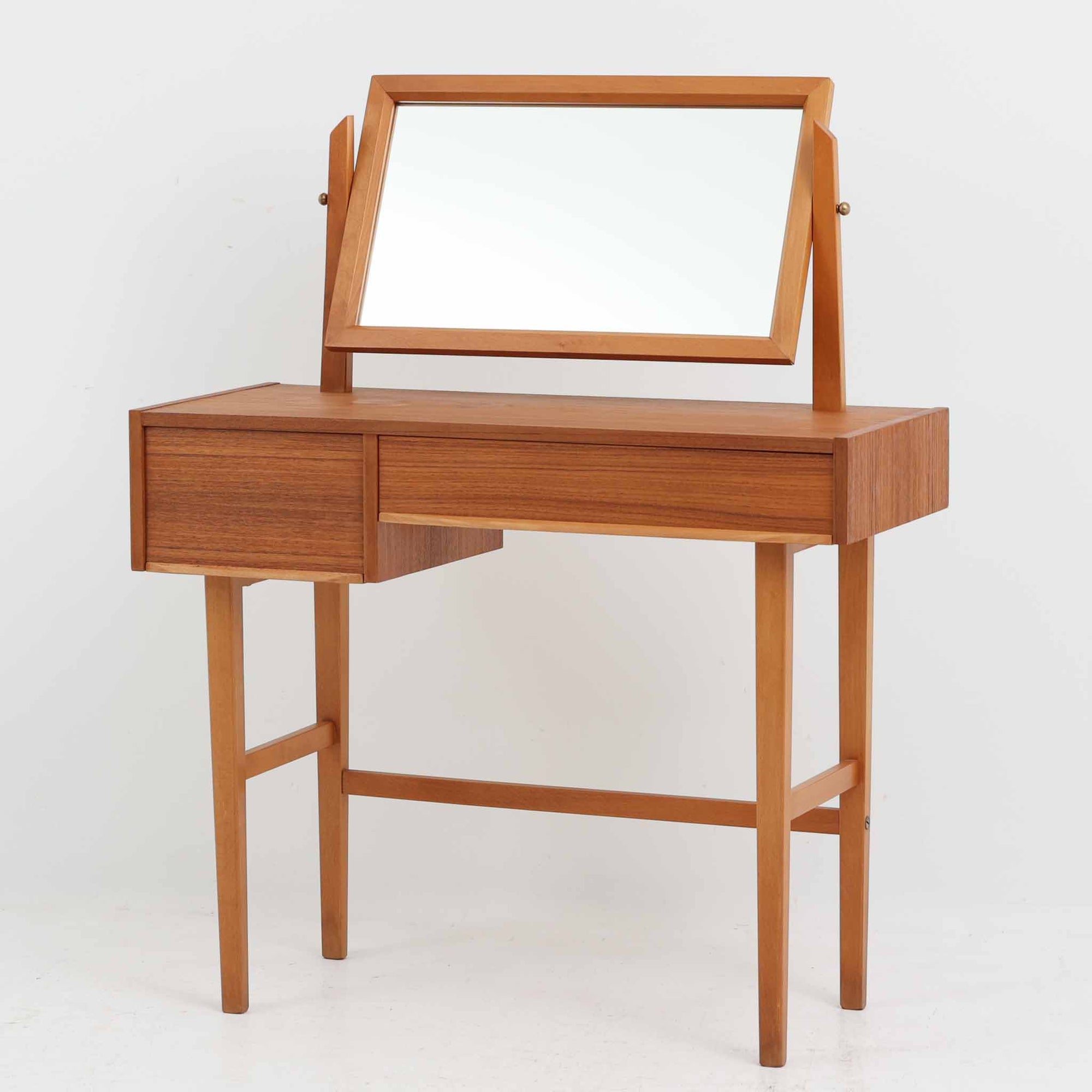 スウェーデン製の北欧ビンテージドレッサーで、チーク材とビーチ材を組み合わせた温かみある質感が魅力です。幅83cmとコンパクトながら、大小2杯の引き出しを備え、内部には仕切りもあり小物の整理に便利です。上部のミラーは角度調整が可能で、実用性と美観を兼ね備えています。直線的で軽快な脚部デザインが空間にすっきりとした印象を与え、経年による木肌の風合いが味わい深さを引き立てています。寝室や玄関先でも活躍する実用的かつ上品な一台です。