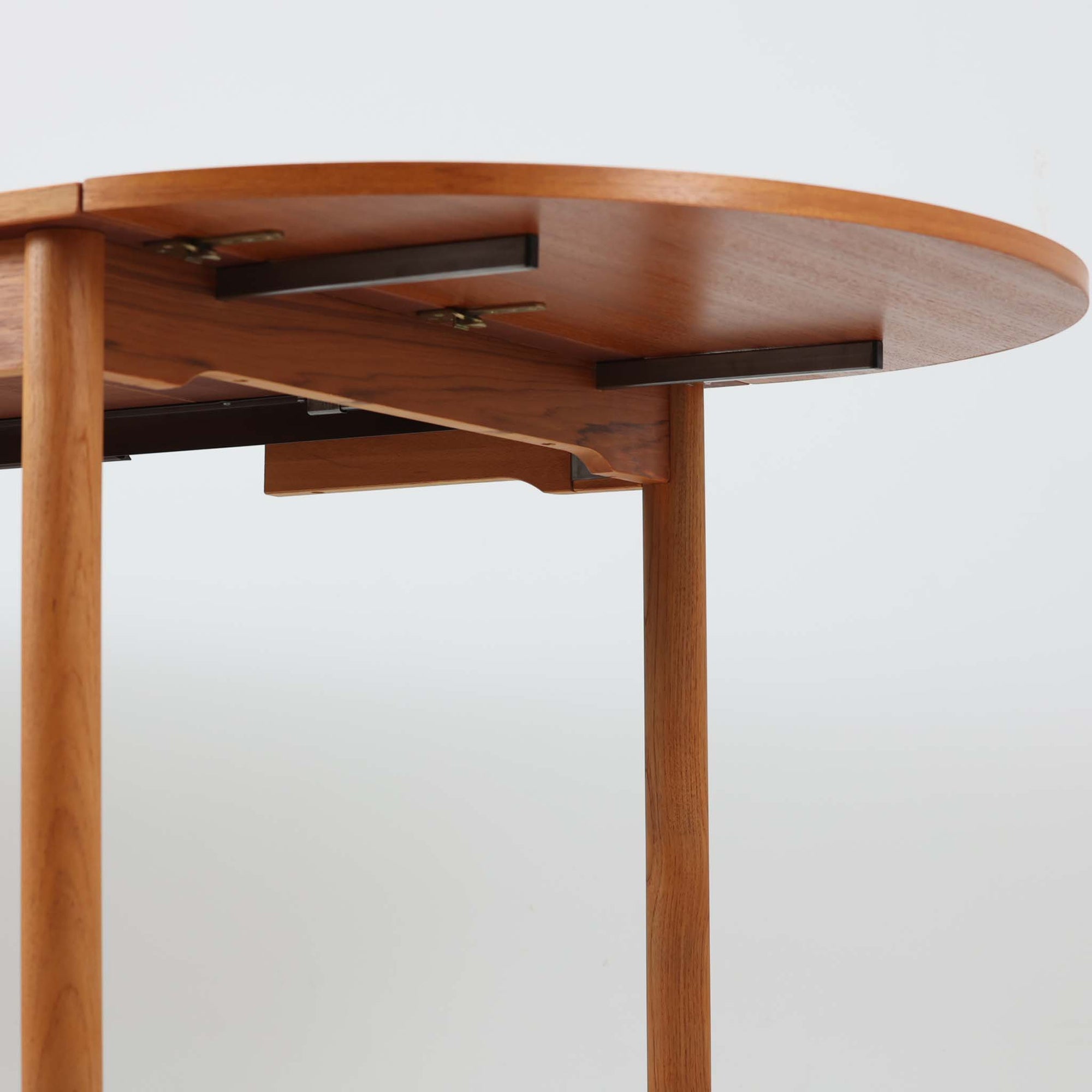 バタフライ式の半円天板と中央拡張板2枚を備えたエクステンションダイニングテーブルは、最大幅2520mmで8人でもゆったり囲めるサイズ感が魅力です。滑らかな金属レール構造により拡張もスムーズで、コンパクトな状態から広々とした食卓へ柔軟に変化します。温かみあるチーク材の質感と端正なデザインが調和した、北欧ビンテージ家具らしい実用性と美しさを兼ね備えた一台です。