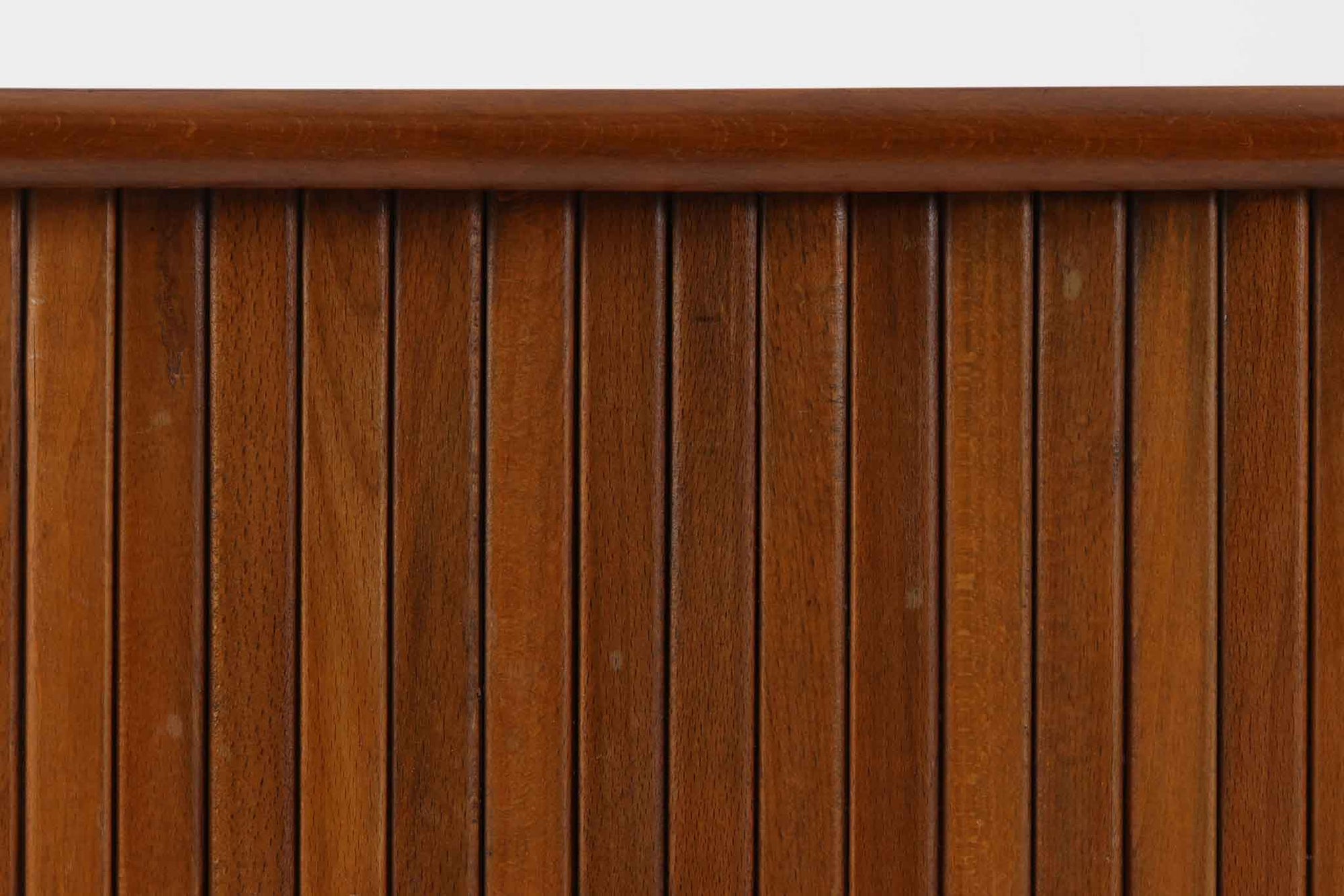 北欧デンマークで製造された、蛇腹扉が特徴的なビンテージキャビネットです。素材にはビーチ材と思われる無垢材や突板が使用されており、ステイン塗装により落ち着いたブラウンカラーに仕上げられています。前面には細かな縦ラインが連続する蛇腹扉が配され、開閉時に滑らかに動く美しい構造が魅力です。内部には棚板が一枚付属しており、収納としての機能性も十分です。丸脚や小さな丸い取っ手も北欧らしい柔らかなディテールで、リビングや玄関、寝室などさまざまな空間に自然に溶け込む一台です。