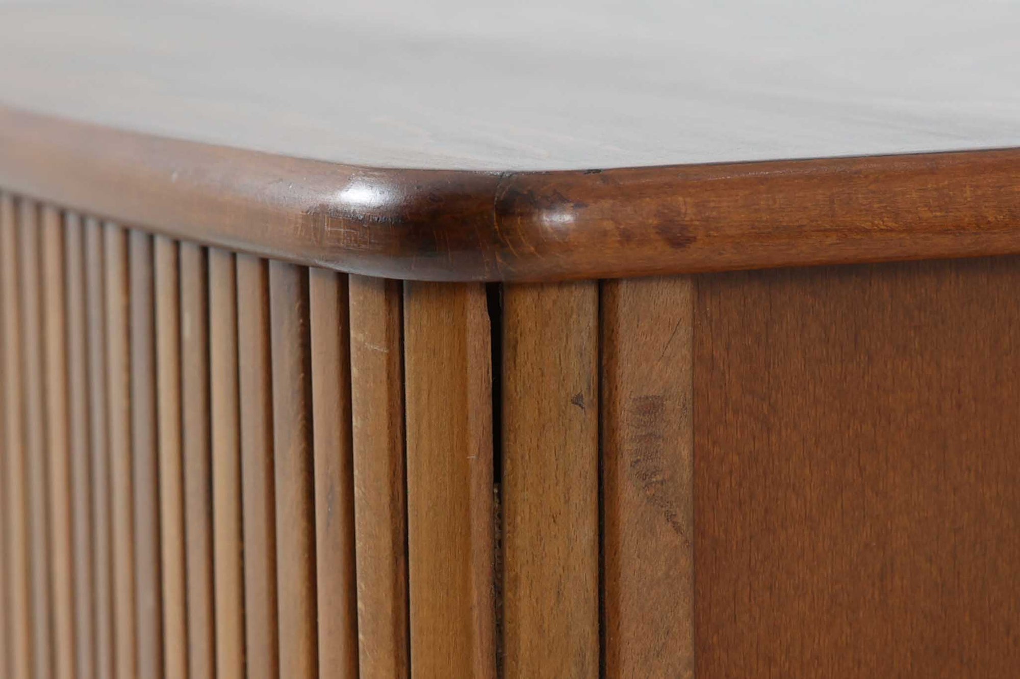 北欧デンマークで製造された、蛇腹扉が特徴的なビンテージキャビネットです。素材にはビーチ材と思われる無垢材や突板が使用されており、ステイン塗装により落ち着いたブラウンカラーに仕上げられています。前面には細かな縦ラインが連続する蛇腹扉が配され、開閉時に滑らかに動く美しい構造が魅力です。内部には棚板が一枚付属しており、収納としての機能性も十分です。丸脚や小さな丸い取っ手も北欧らしい柔らかなディテールで、リビングや玄関、寝室などさまざまな空間に自然に溶け込む一台です。