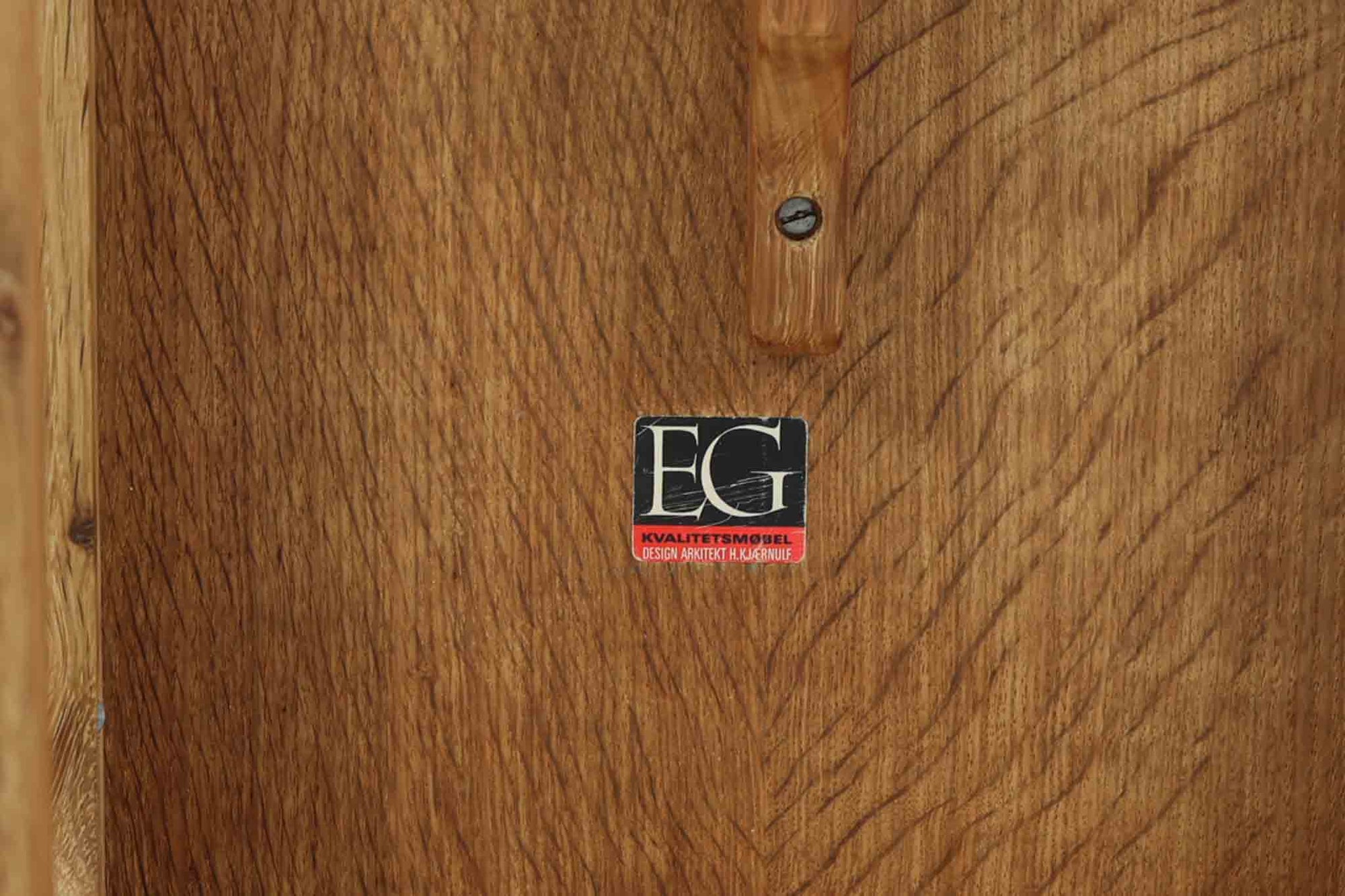 デンマークの建築家Henning Kjaernulf（ヘニング・ケアヌルフ）によってデザインされた、オーク無垢材のドロップリーフ式センターテーブルです。製造は高品質な家具で知られるEGモブラー社。無垢材ならではの美しい木目と、クラシカルで彫刻的な脚部のラインが印象的です。天板は両側に開閉式のリーフが備わっており、来客時や作業時には広げてスペースを拡張できるなど、実用性も兼ね備えています。高さ約51cmとやや高めの設計で、ソファ前に置いても手元が使いやすく、センターテーブルとして快適にお使いいただけます。必要に応じてサイドテーブルやティーテーブルとしても活躍する、用途の広い一台です。