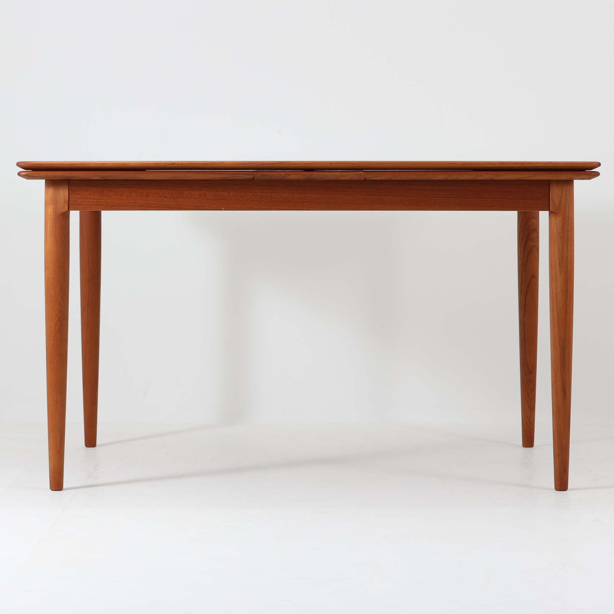 チーク材の温かみある風合いと洗練されたシルエットが魅力のエクステンションダイニングテーブルです。デザイナーは不明ですが、脚部や拡張板の形状など、細部にまでこだわりが感じられる上質な一品です。