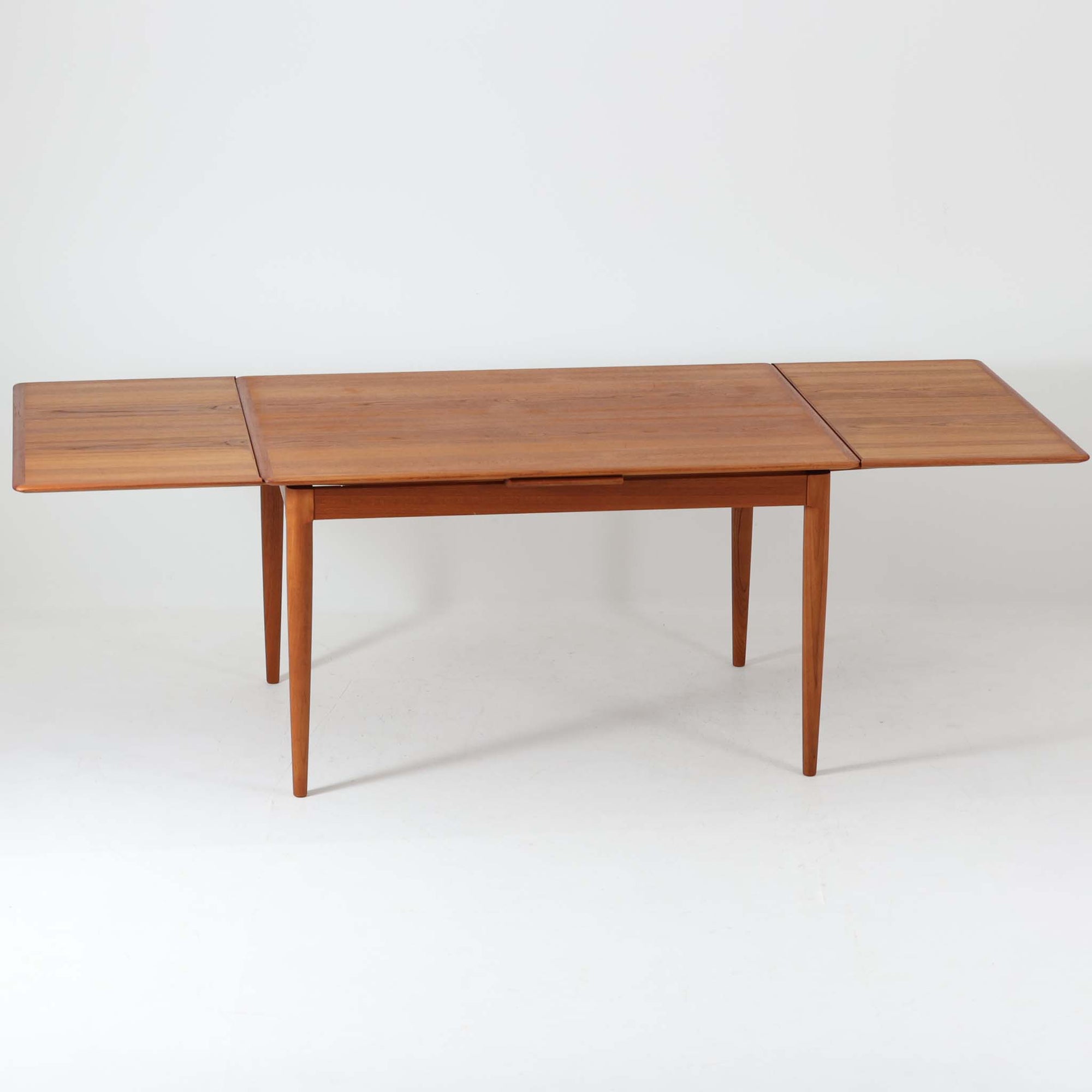 チーク材の温かみある風合いと洗練されたシルエットが魅力のエクステンションダイニングテーブルです。デザイナーは不明ですが、脚部や拡張板の形状など、細部にまでこだわりが感じられる上質な一品です。