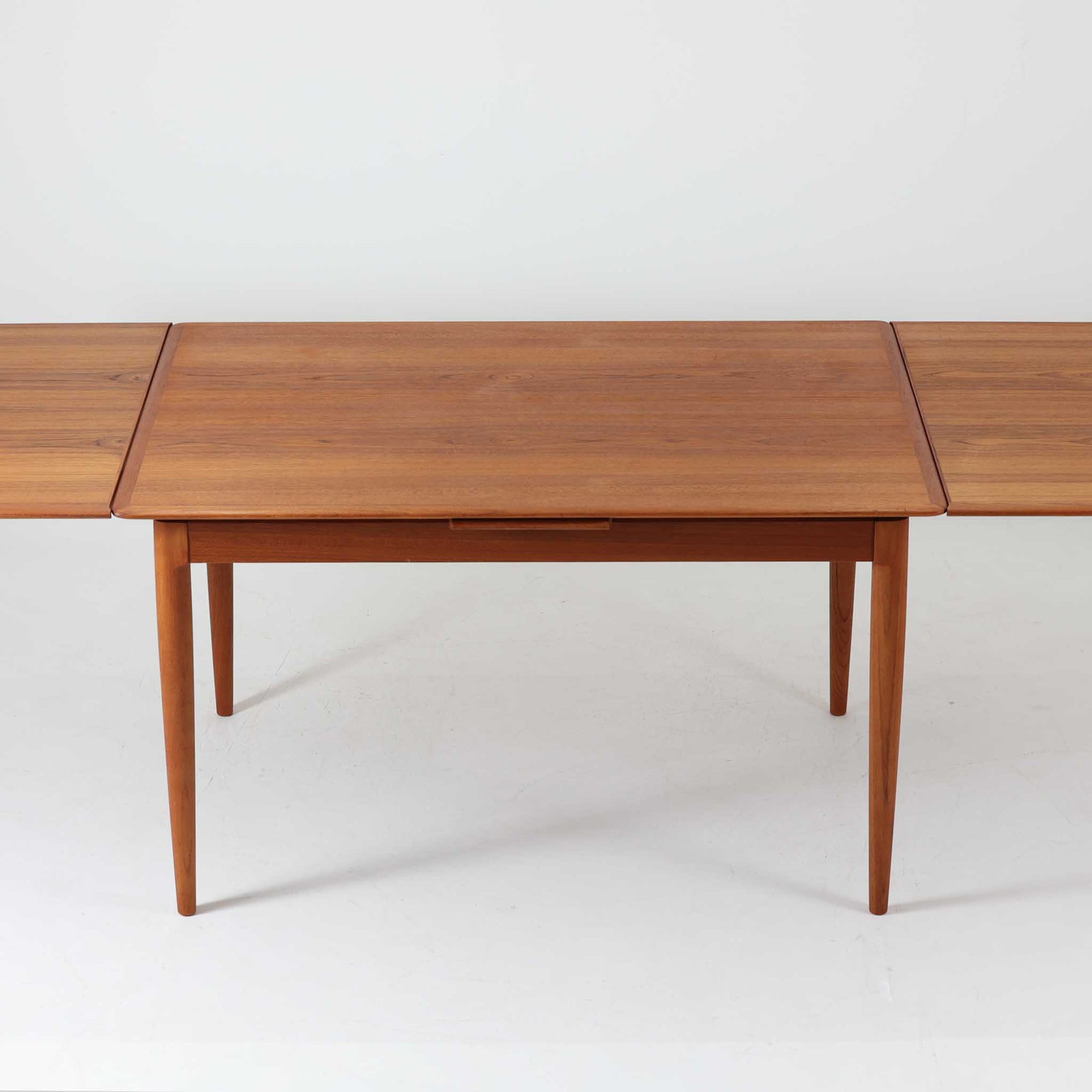 チーク材の温かみある風合いと洗練されたシルエットが魅力のエクステンションダイニングテーブルです。デザイナーは不明ですが、脚部や拡張板の形状など、細部にまでこだわりが感じられる上質な一品です。