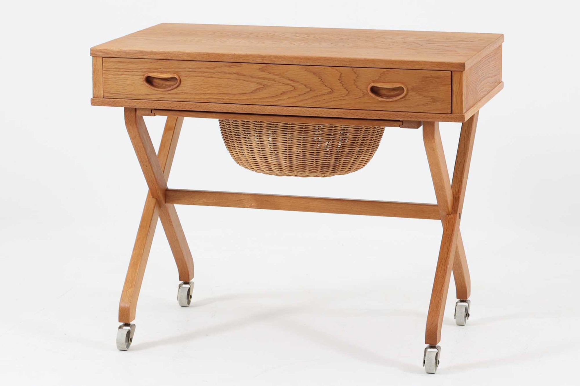 デンマーク製のビンテージ・ソーイングテーブルです。天板下には大きな引き出しが備わっており、裁縫道具や小物を収納するのに最適です。また、中央には籐製のバスケットが付属しており、毛糸や生地などを入れるのに便利な作りとなっています。脚部は交差したデザインが特徴的で、軽やかな印象を与えます。キャスター付きのため移動もスムーズで、リビングやワークスペースなどさまざまな場所で活躍します。シンプルながらも温かみのあるデザインは、北欧家具ならではの魅力。ソーイングテーブルとしてはもちろん、サイドテーブルとしてもお使いいただけます。