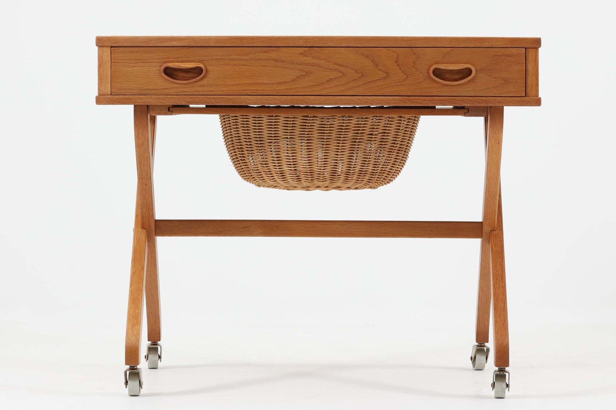 デンマーク製のビンテージ・ソーイングテーブルです。天板下には大きな引き出しが備わっており、裁縫道具や小物を収納するのに最適です。また、中央には籐製のバスケットが付属しており、毛糸や生地などを入れるのに便利な作りとなっています。脚部は交差したデザインが特徴的で、軽やかな印象を与えます。キャスター付きのため移動もスムーズで、リビングやワークスペースなどさまざまな場所で活躍します。シンプルながらも温かみのあるデザインは、北欧家具ならではの魅力。ソーイングテーブルとしてはもちろん、サイドテーブルとしてもお使いいただけます。