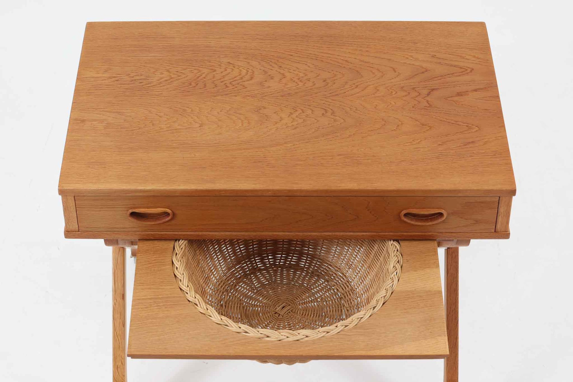 デンマーク製のビンテージ・ソーイングテーブルです。天板下には大きな引き出しが備わっており、裁縫道具や小物を収納するのに最適です。また、中央には籐製のバスケットが付属しており、毛糸や生地などを入れるのに便利な作りとなっています。脚部は交差したデザインが特徴的で、軽やかな印象を与えます。キャスター付きのため移動もスムーズで、リビングやワークスペースなどさまざまな場所で活躍します。シンプルながらも温かみのあるデザインは、北欧家具ならではの魅力。ソーイングテーブルとしてはもちろん、サイドテーブルとしてもお使いいただけます。