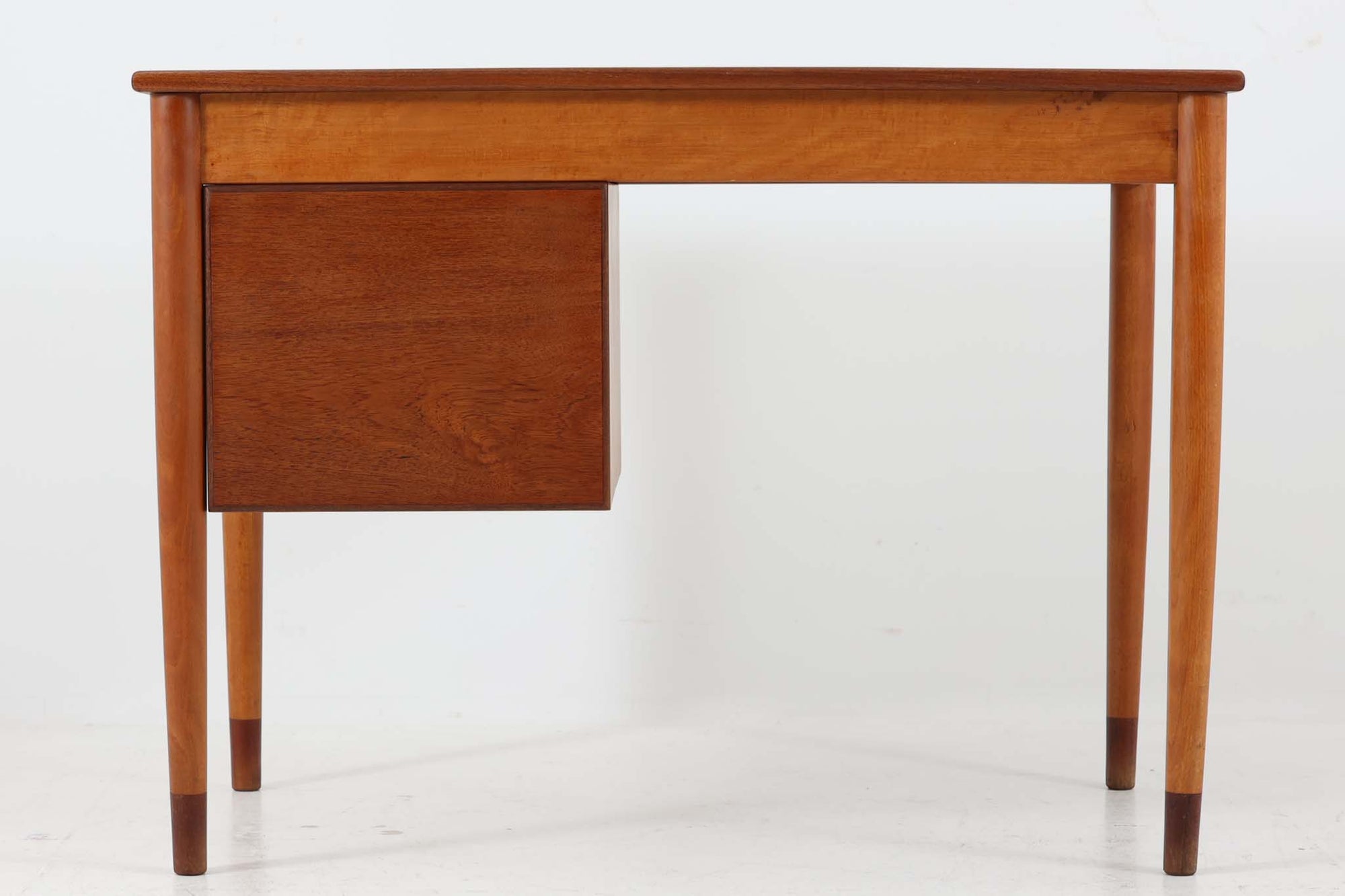 Borge mogensenデザインの小ぶりな片袖デスクは、モーエンセンらしい上質なオーク材が使用された美しいモデルです。デザインの特徴である引き出しの取手も、細部にわたるこだわりが感じられます。本体にはチーク材、脚にはビーチ材が使用され、デンマークの室内靴文化に配慮して、足元には汚れが目立たない濃い色味のチーク材がジョイントされています。洗練されたデザインと実用性を兼ね備えたこのデスクは、どんなインテリアにもマッチするアイテムです。