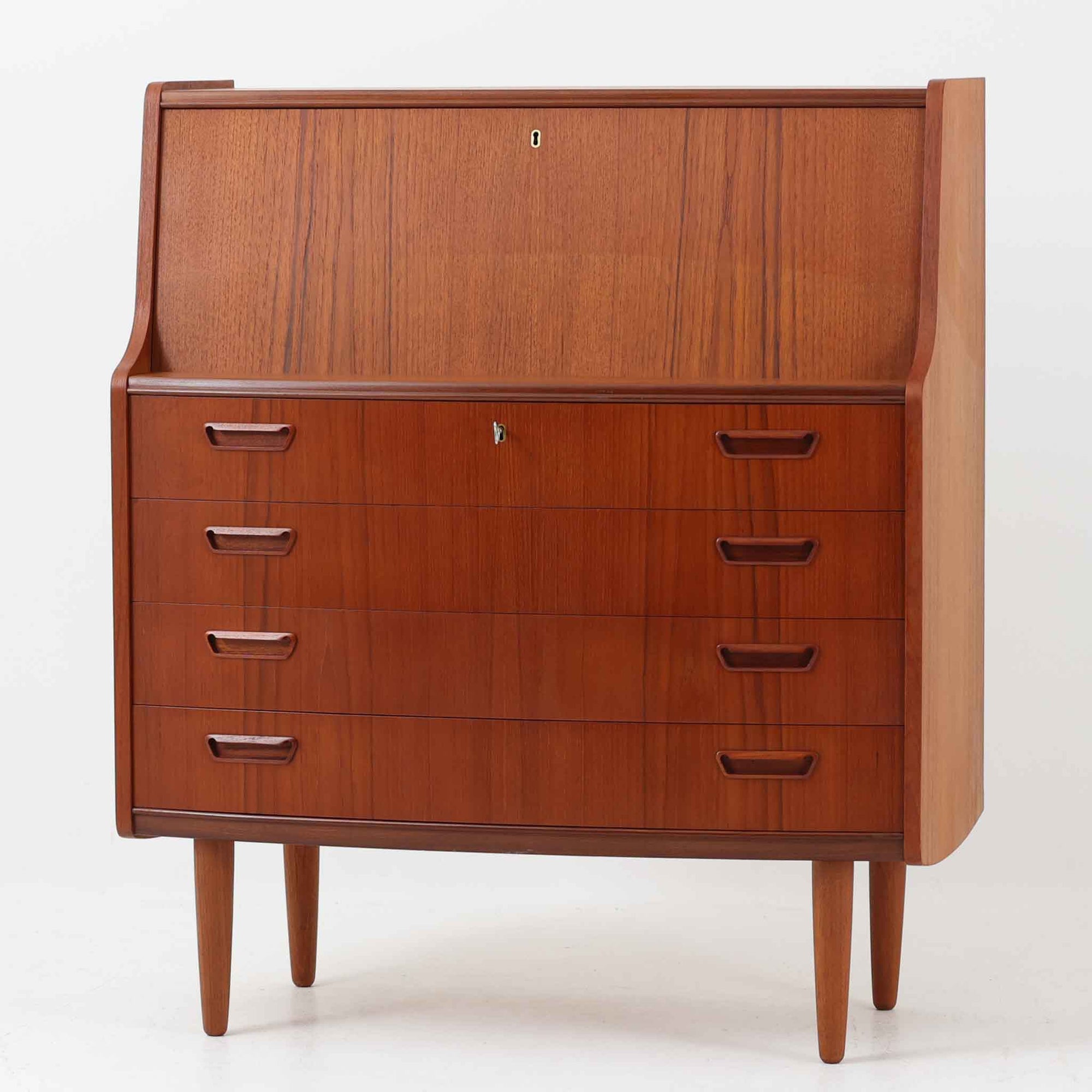 Poul M.Jessenによるこちらのライティングビューロは、PMJ Viby社製の北欧ビンテージ家具で、美しい木目のチーク材を用いた上品な佇まいが魅力です。緩やかにカーブした側面や繊細な取手の意匠、引き出しと小さな収納棚を備えたライティングスペースなど、機能性とデザイン性が見事に調和しています。幅92cmの程よいサイズ感で、リビングや寝室のデスク兼収納としても活躍し、空間に静かな存在感を添える一台です。