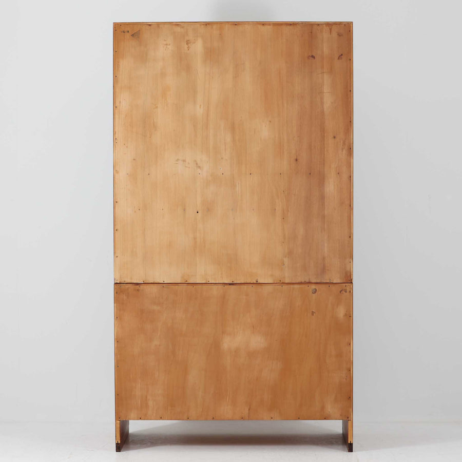 Hans J. Wegnerがデザインし、Ry Mobler社より製造されたこちらのディスプレイシェルフは、チーク材の上質な素材使いと真鍮パーツのディテールが際立つ北欧ビンテージ家具です。シンプルな直線的フォルムの中に、扉付き収納、ドロップダウン式のビューロスペース、小引き出しや仕切り棚など機能的な構造が備わっており、書斎でのデスク兼収納やリビングの飾り棚として多用途に活躍します。年月を経て深みを増した木肌が空間に落ち着いた存在感を与える逸品です。