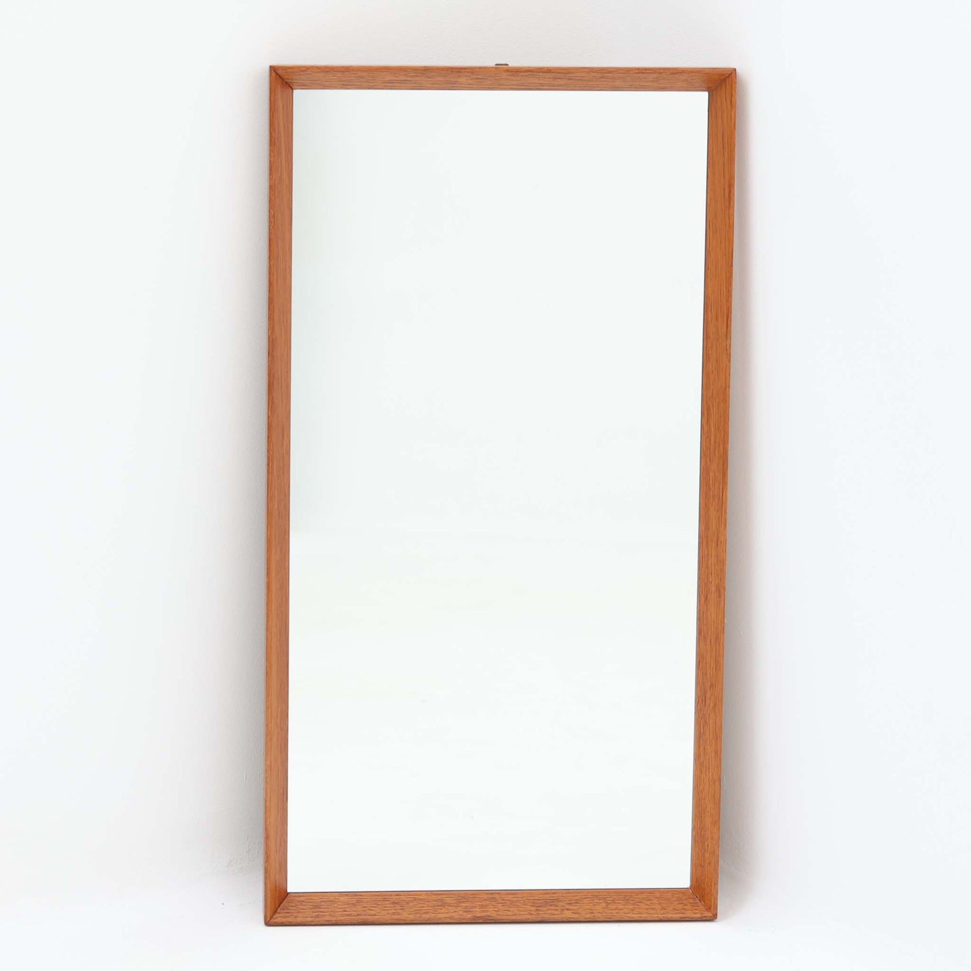すっきりとしたフレームデザインが印象的なこちらのミラーは、チーク材を用いた北欧ビンテージ品で、壁掛けはもちろん立て掛けても使用できる柔軟な仕様が魅力です。高さ69cmの程よいサイズ感で、玄関やリビング、寝室の空間に溶け込みやすく、自然な木目の美しさと温かみが空間を引き立てます。背面にはモデルナンバーの刻印も残り、ビンテージならではの風合いを備えた一品です。