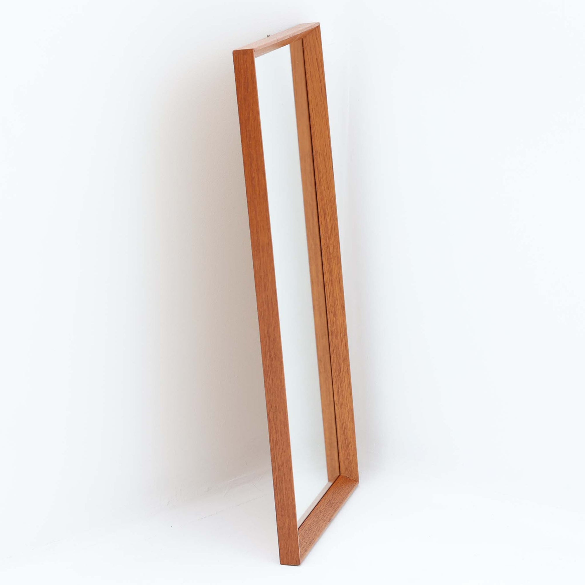 すっきりとしたフレームデザインが印象的なこちらのミラーは、チーク材を用いた北欧ビンテージ品で、壁掛けはもちろん立て掛けても使用できる柔軟な仕様が魅力です。高さ69cmの程よいサイズ感で、玄関やリビング、寝室の空間に溶け込みやすく、自然な木目の美しさと温かみが空間を引き立てます。背面にはモデルナンバーの刻印も残り、ビンテージならではの風合いを備えた一品です。