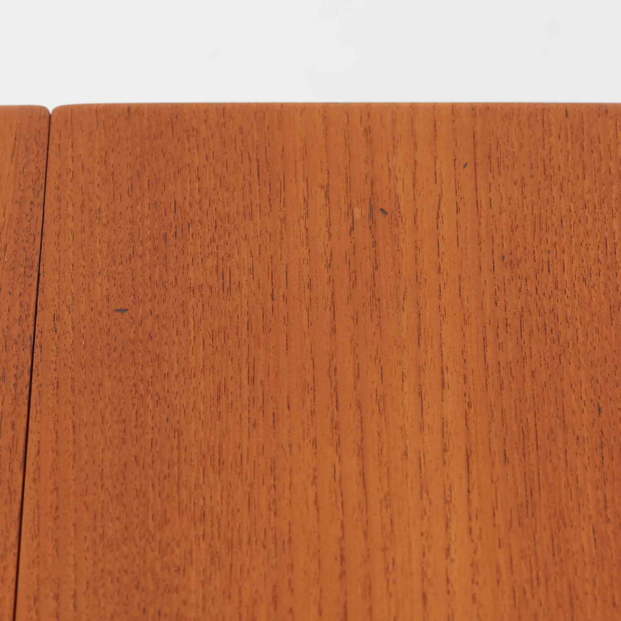 Hans J. Wegnerがデザインし、Andreas Tuck社から発表されたAT33ソーイングテーブルは、チーク無垢材を贅沢に用いた希少なモデルです。両側のバタフライ式天板で作業スペースを拡張でき、仕切り付きの引き出しとラタン製バスケットが裁縫道具や小物を美しく収納します。下段の棚板も備えた実用性の高い構造で、繊細な造作と職人技が光る北欧ビンテージ家具の逸品です。