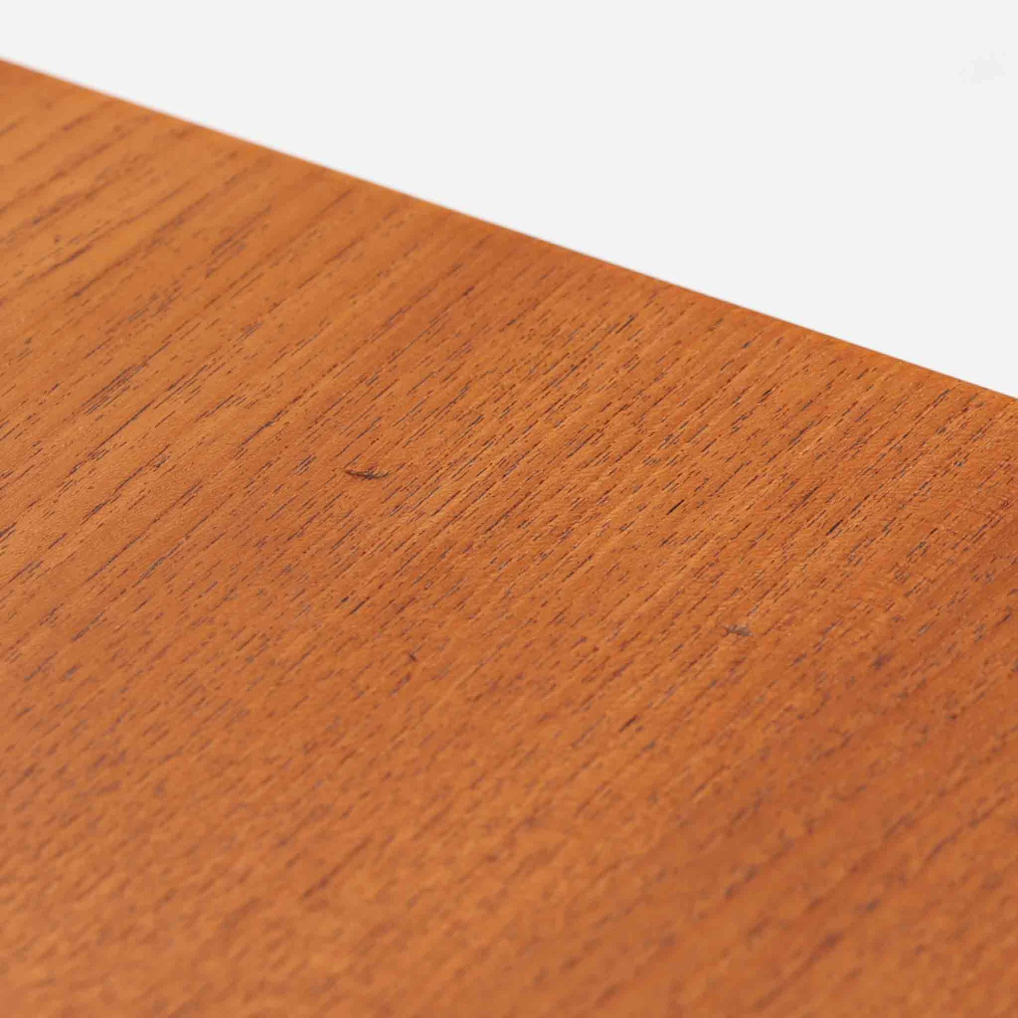 Hans J. Wegnerがデザインし、Andreas Tuck社から発表されたAT33ソーイングテーブルは、チーク無垢材を贅沢に用いた希少なモデルです。両側のバタフライ式天板で作業スペースを拡張でき、仕切り付きの引き出しとラタン製バスケットが裁縫道具や小物を美しく収納します。下段の棚板も備えた実用性の高い構造で、繊細な造作と職人技が光る北欧ビンテージ家具の逸品です。