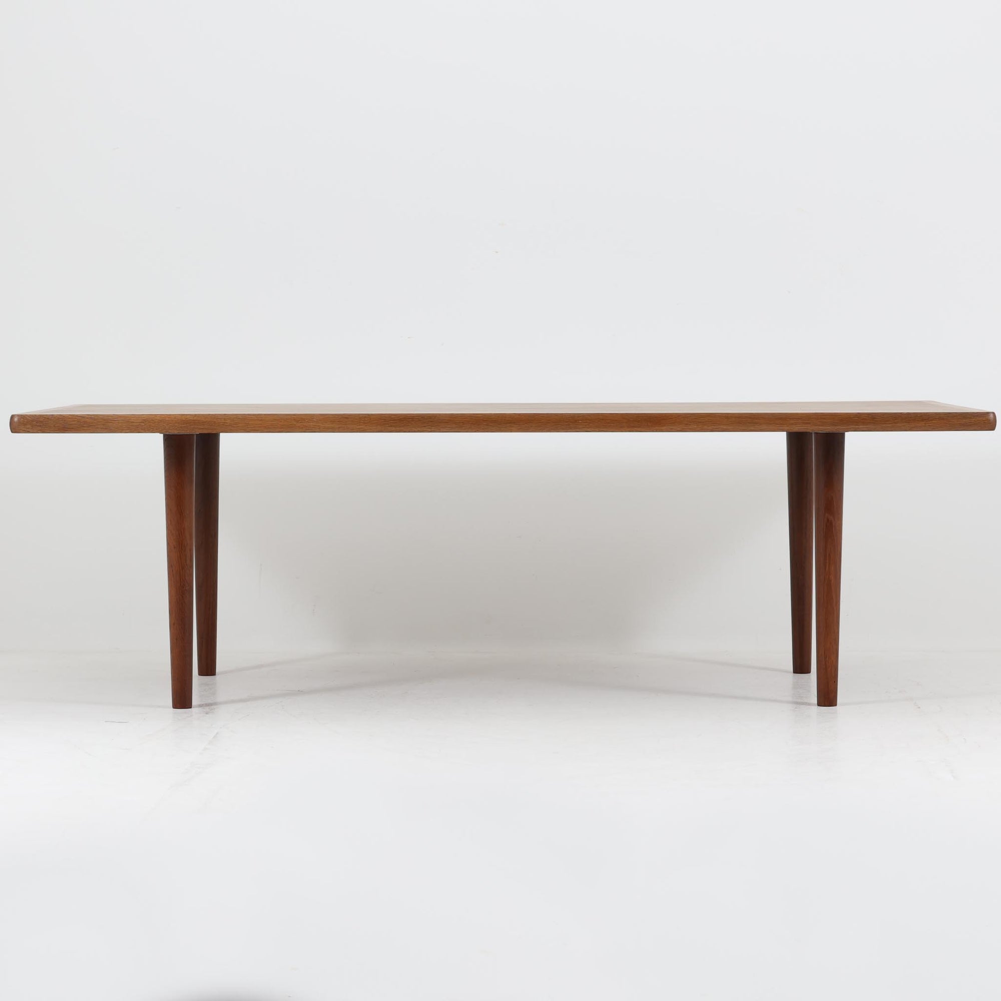Hans J. Wegnerがデザインし、Getama社より製造されたこちらのセンターテーブルは、幅170cmのゆったりとしたサイズ感と、直線的でシンプルなフォルムが特徴の北欧ビンテージ家具です。ダークオーク材の深みある木目と温かな色調が空間に落ち着きを与え、テーパー状の脚部が軽やかな印象を演出します。リビングでのメインテーブルとしてはもちろん、ソファ前のゆったりとした空間演出にも最適で、年月を経て味わいを増した存在感を楽しめる逸品です。