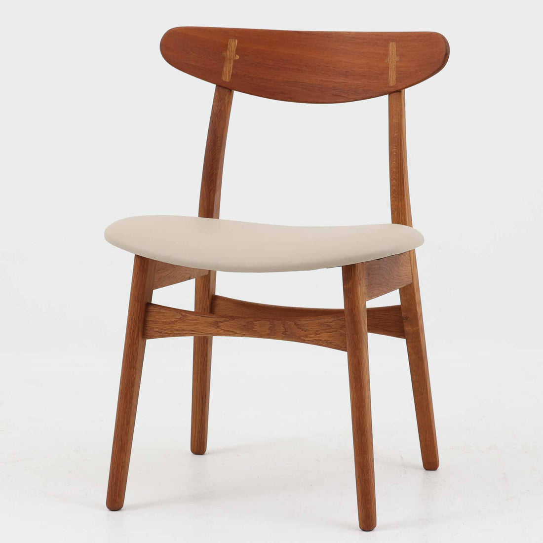 Hans J. Wegnerがデザインし、Carl Hansen & Son社によって製造されたCH30は、チーク材とオーク材を組み合わせた北欧ビンテージらしい温もりある佇まいと、背もたれに施されたフィンガージョイントがアクセントとなる美しいダイニングチェアです。丸みを帯びた背もたれと座面の柔らかなフォルムが身体に心地よくフィットし、長時間の着座でも快適な座り心地を提供します。座面はアイボリー系の合皮で張替済み、実用性と清潔感を兼ね備えており、日常使いから来客用まで幅広いシーンで活躍します。