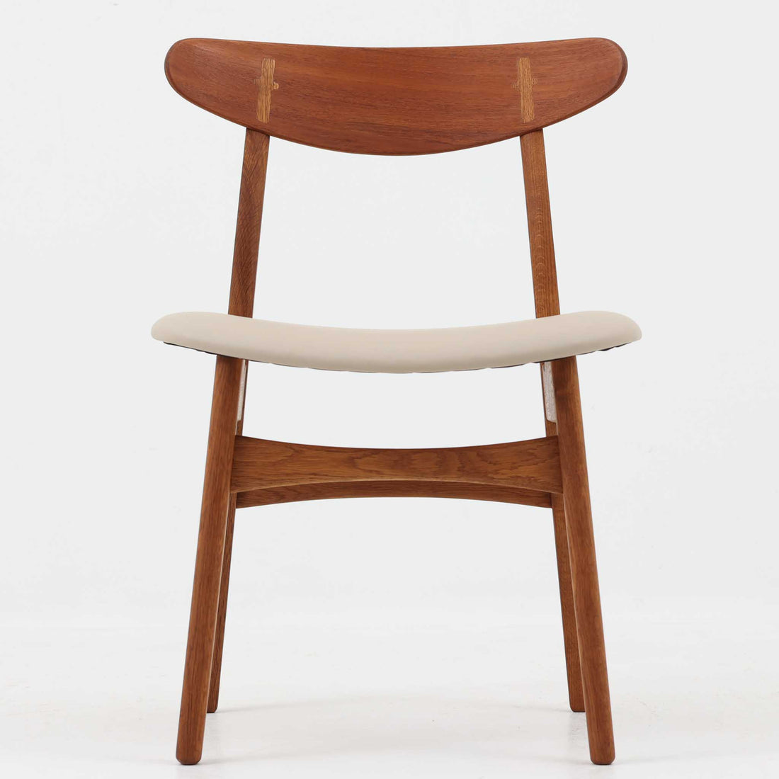 Hans J. Wegnerがデザインし、Carl Hansen & Son社によって製造されたCH30は、チーク材とオーク材を組み合わせた北欧ビンテージらしい温もりある佇まいと、背もたれに施されたフィンガージョイントがアクセントとなる美しいダイニングチェアです。丸みを帯びた背もたれと座面の柔らかなフォルムが身体に心地よくフィットし、長時間の着座でも快適な座り心地を提供します。座面はアイボリー系の合皮で張替済み、実用性と清潔感を兼ね備えており、日常使いから来客用まで幅広いシーンで活躍します。