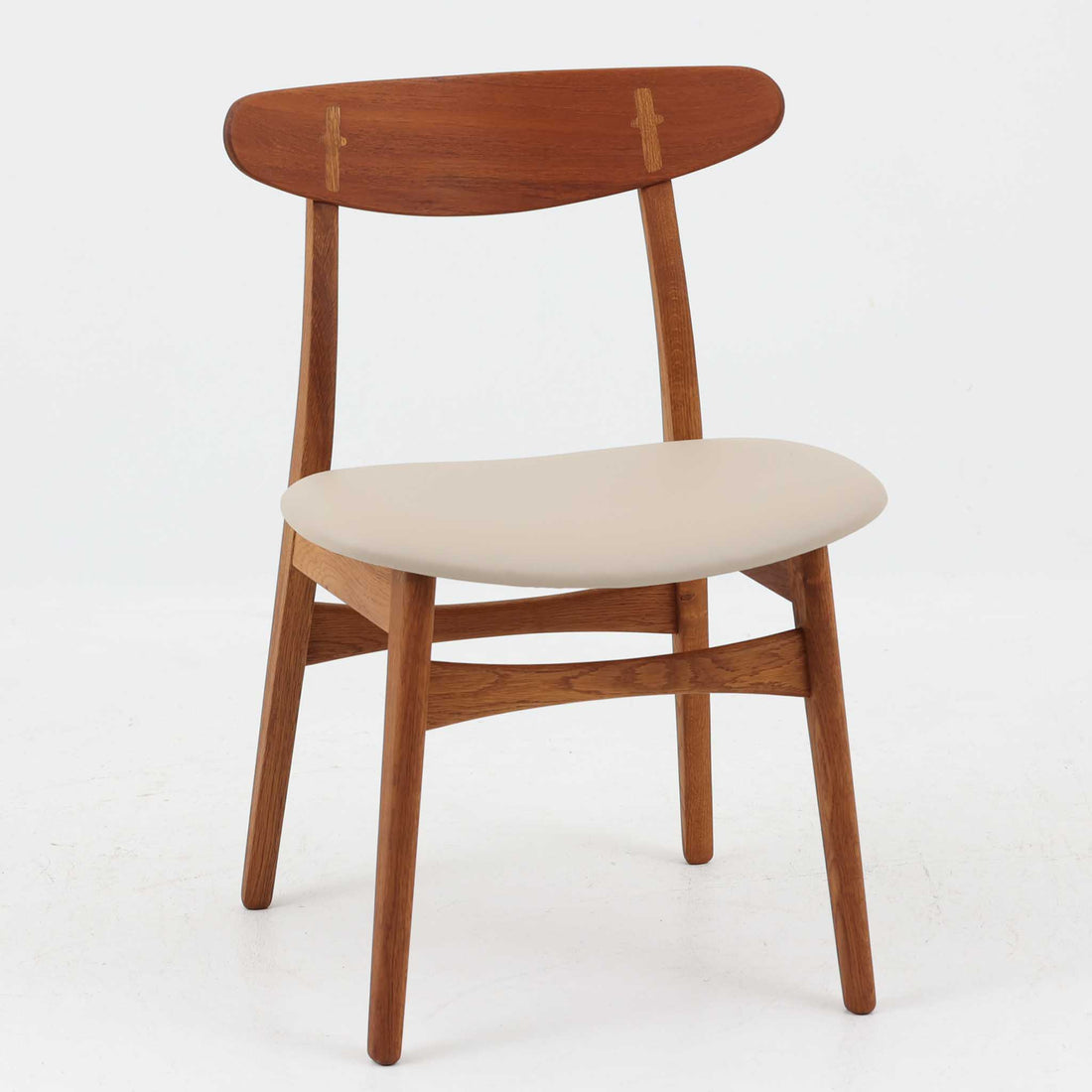 Hans J. Wegnerがデザインし、Carl Hansen & Son社によって製造されたCH30は、チーク材とオーク材を組み合わせた北欧ビンテージらしい温もりある佇まいと、背もたれに施されたフィンガージョイントがアクセントとなる美しいダイニングチェアです。丸みを帯びた背もたれと座面の柔らかなフォルムが身体に心地よくフィットし、長時間の着座でも快適な座り心地を提供します。座面はアイボリー系の合皮で張替済み、実用性と清潔感を兼ね備えており、日常使いから来客用まで幅広いシーンで活躍します。