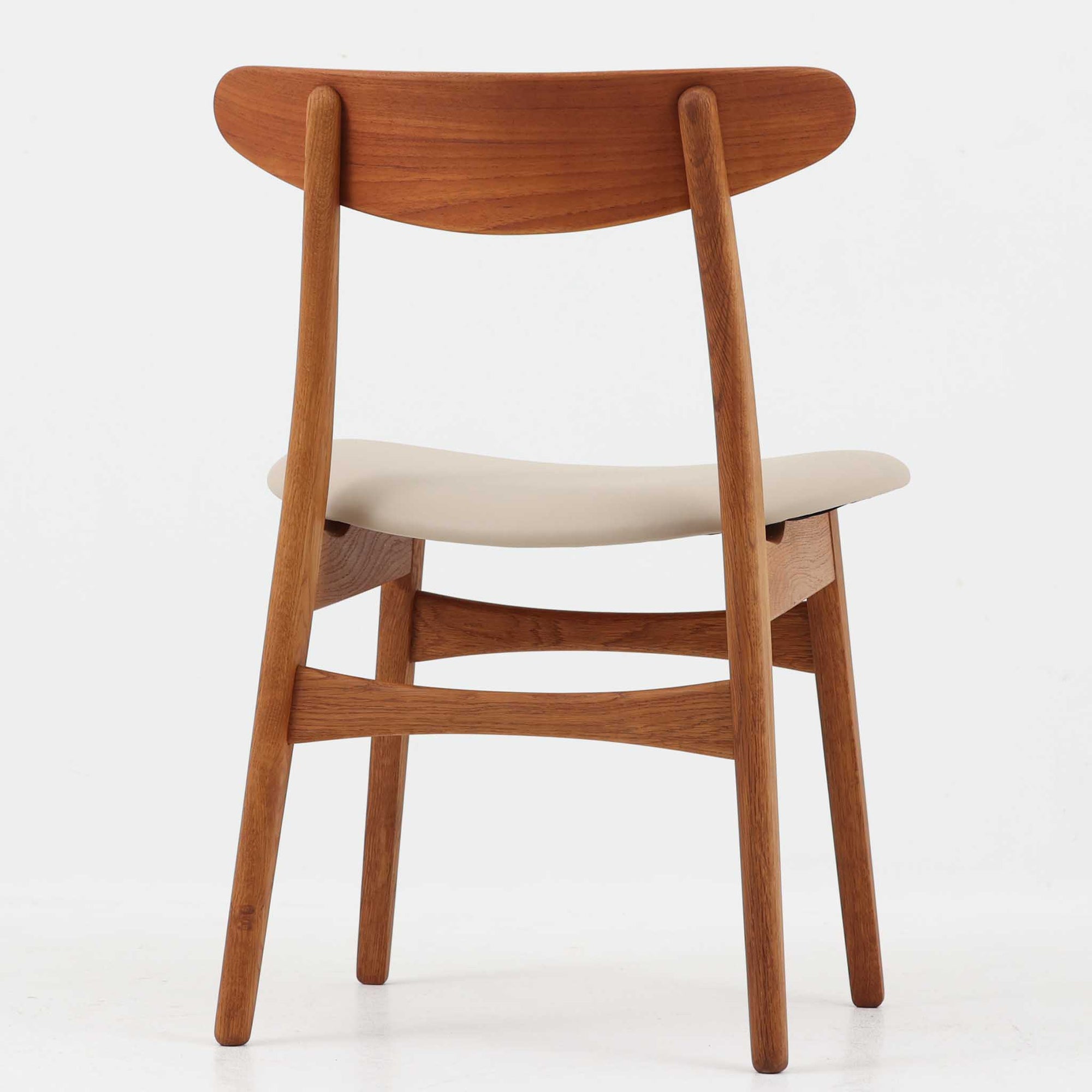 Hans J. Wegnerがデザインし、Carl Hansen &amp; Son社によって製造されたCH30は、チーク材とオーク材を組み合わせた北欧ビンテージらしい温もりある佇まいと、背もたれに施されたフィンガージョイントがアクセントとなる美しいダイニングチェアです。丸みを帯びた背もたれと座面の柔らかなフォルムが身体に心地よくフィットし、長時間の着座でも快適な座り心地を提供します。座面はアイボリー系の合皮で張替済み、実用性と清潔感を兼ね備えており、日常使いから来客用まで幅広いシーンで活躍します。