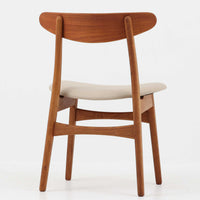 Hans J. Wegnerがデザインし、Carl Hansen & Son社によって製造されたCH30は、チーク材とオーク材を組み合わせた北欧ビンテージらしい温もりある佇まいと、背もたれに施されたフィンガージョイントがアクセントとなる美しいダイニングチェアです。丸みを帯びた背もたれと座面の柔らかなフォルムが身体に心地よくフィットし、長時間の着座でも快適な座り心地を提供します。座面はアイボリー系の合皮で張替済み、実用性と清潔感を兼ね備えており、日常使いから来客用まで幅広いシーンで活躍します。