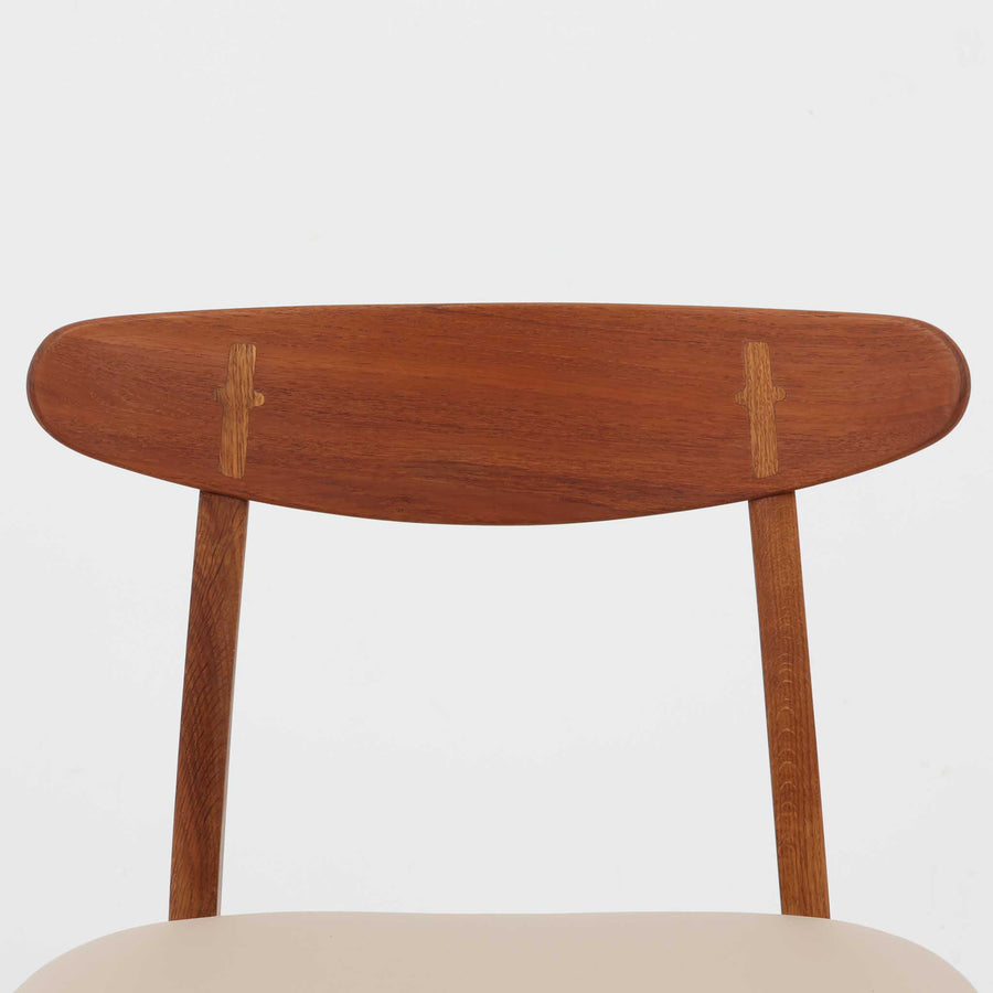 Hans J. Wegnerがデザインし、Carl Hansen & Son社によって製造されたCH30は、チーク材とオーク材を組み合わせた北欧ビンテージらしい温もりある佇まいと、背もたれに施されたフィンガージョイントがアクセントとなる美しいダイニングチェアです。丸みを帯びた背もたれと座面の柔らかなフォルムが身体に心地よくフィットし、長時間の着座でも快適な座り心地を提供します。座面はアイボリー系の合皮で張替済み、実用性と清潔感を兼ね備えており、日常使いから来客用まで幅広いシーンで活躍します。