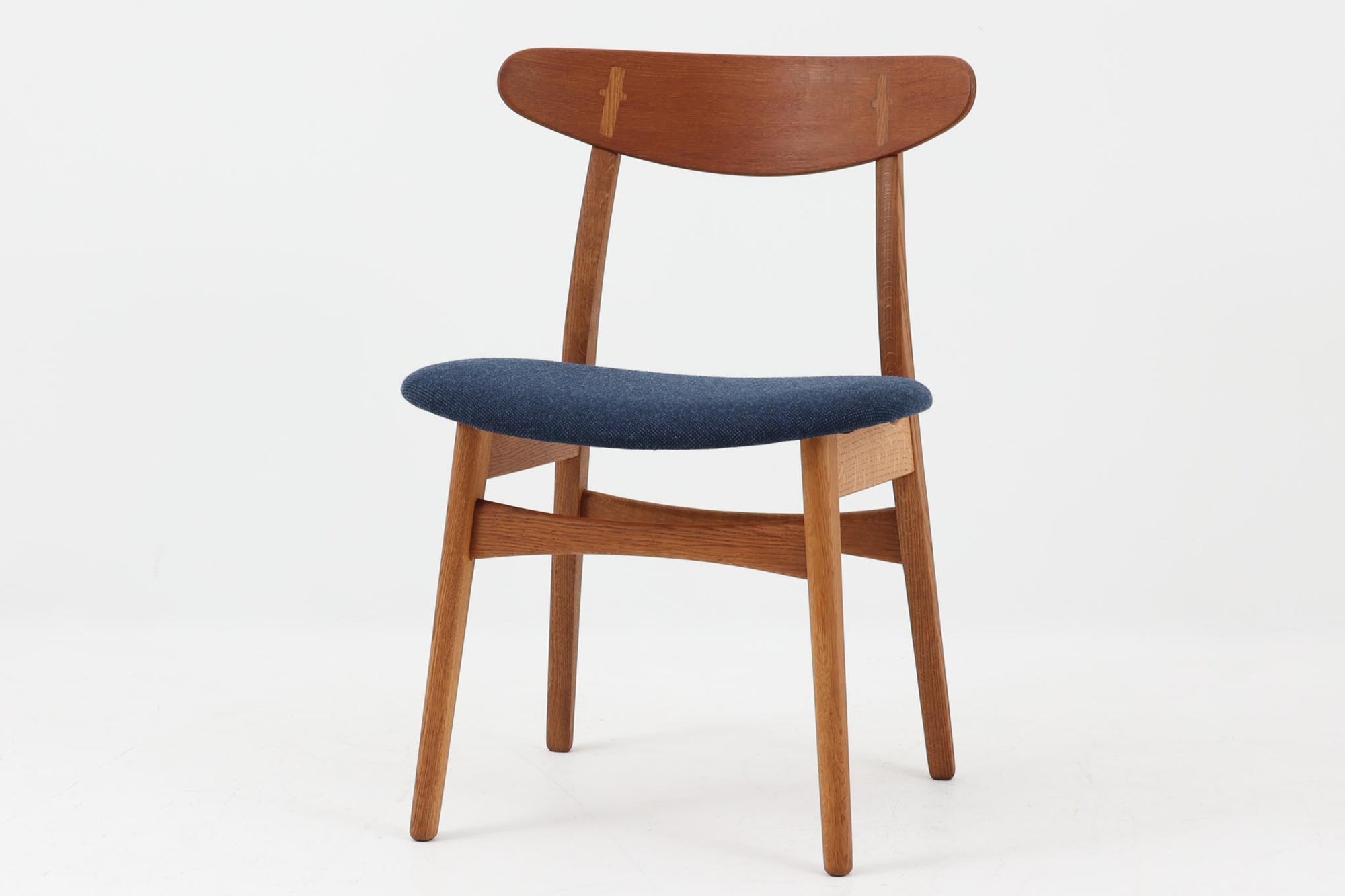 CH30は、ハンス・J・ウェグナーがデザインし、Carl Hansen & Son社によって製造された名作ダイニングチェア。チーク材とオーク材を組み合わせた美しいコントラストが特徴で、木の温もりと洗練されたフォルムが魅力です。特に背もたれと後ろ脚の繋ぎ目は、そのデザインの特徴となっており、独自性とクラフトマンシップの見本と言えるでしょう。背もたれにチーク材が使用された希少なモデルです。人気のため現在復刻されましたが、チーク材とオーク材の組み合わせはビンテージ品でのみ入手可能です。