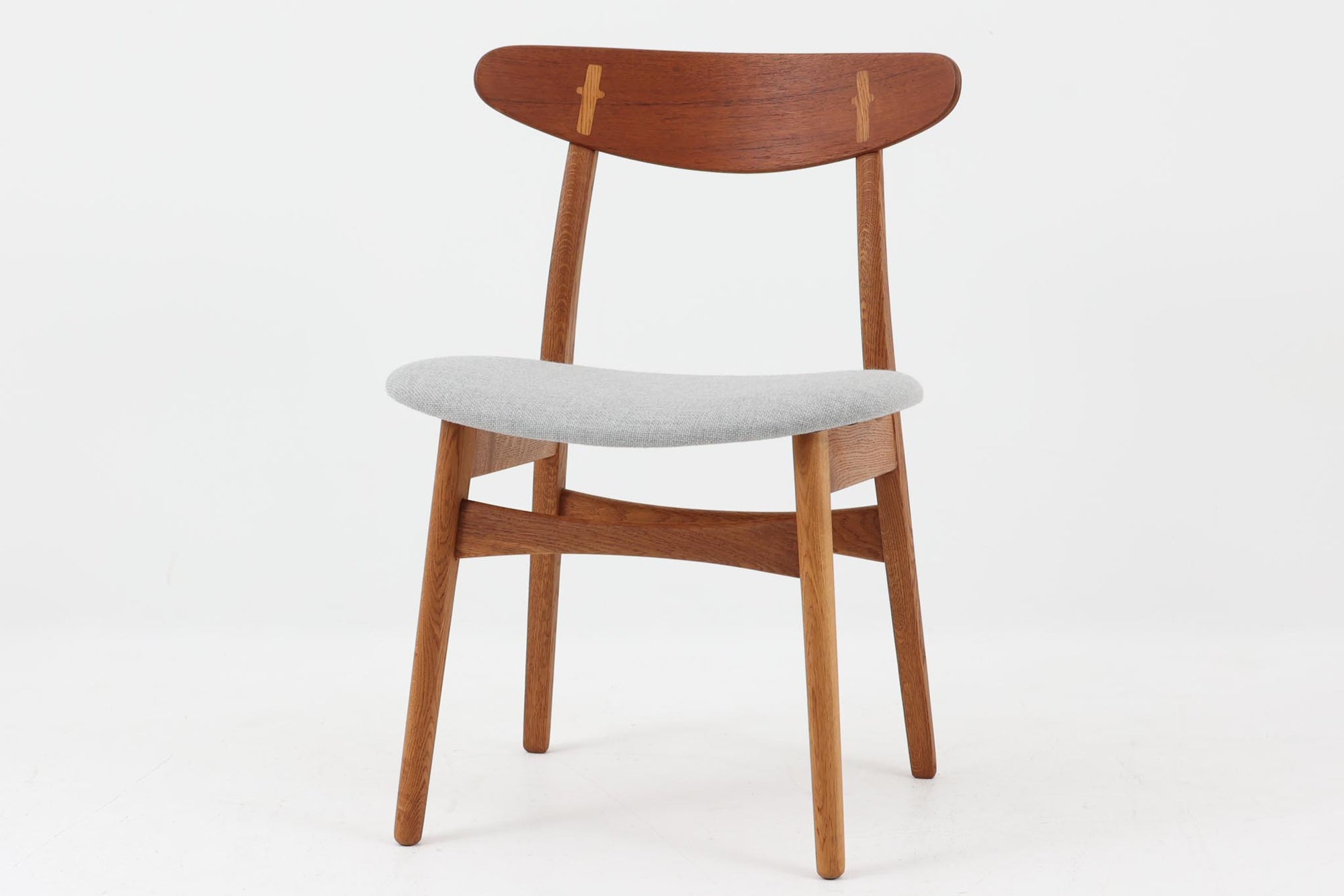 CH30は、ハンス・J・ウェグナーがデザインし、Carl Hansen & Son社によって製造された名作ダイニングチェア。チーク材とオーク材を組み合わせた美しいコントラストが特徴で、木の温もりと洗練されたフォルムが魅力です。特に背もたれと後ろ脚の繋ぎ目は、そのデザインの特徴となっており、独自性とクラフトマンシップの見本と言えるでしょう。背もたれにチーク材が使用された希少なモデルです。人気のため現在復刻されましたが、チーク材とオーク材の組み合わせはビンテージ品でのみ入手可能です。