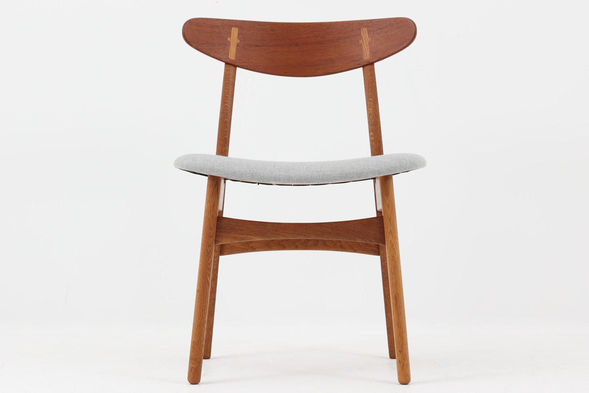 CH30は、ハンス・J・ウェグナーがデザインし、Carl Hansen & Son社によって製造された名作ダイニングチェア。チーク材とオーク材を組み合わせた美しいコントラストが特徴で、木の温もりと洗練されたフォルムが魅力です。特に背もたれと後ろ脚の繋ぎ目は、そのデザインの特徴となっており、独自性とクラフトマンシップの見本と言えるでしょう。背もたれにチーク材が使用された希少なモデルです。人気のため現在復刻されましたが、チーク材とオーク材の組み合わせはビンテージ品でのみ入手可能です。