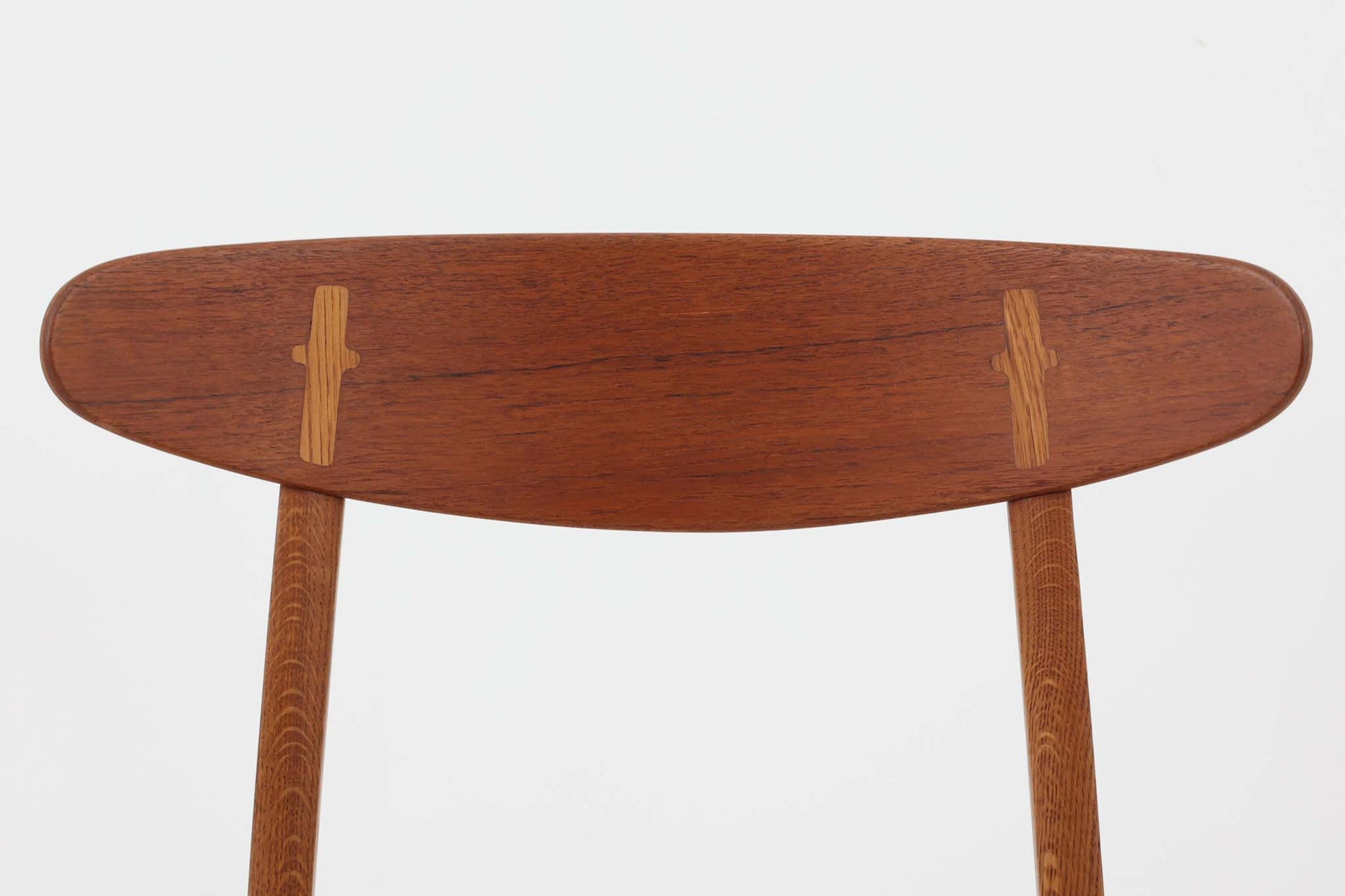 CH30は、ハンス・J・ウェグナーがデザインし、Carl Hansen &amp; Son社によって製造された名作ダイニングチェア。チーク材とオーク材を組み合わせた美しいコントラストが特徴で、木の温もりと洗練されたフォルムが魅力です。特に背もたれと後ろ脚の繋ぎ目は、そのデザインの特徴となっており、独自性とクラフトマンシップの見本と言えるでしょう。背もたれにチーク材が使用された希少なモデルです。人気のため現在復刻されましたが、チーク材とオーク材の組み合わせはビンテージ品でのみ入手可能です。