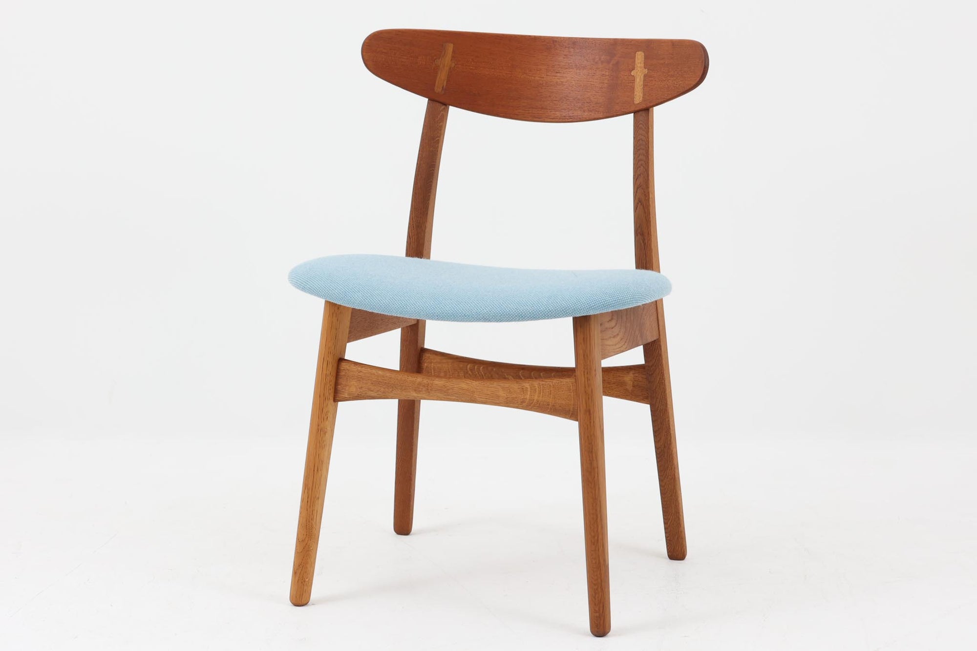 CH30は、ハンス・J・ウェグナーがデザインし、Carl Hansen & Son社によって製造された名作ダイニングチェア。チーク材とオーク材を組み合わせた美しいコントラストが特徴で、木の温もりと洗練されたフォルムが魅力です。特に背もたれと後ろ脚の繋ぎ目は、そのデザインの特徴となっており、独自性とクラフトマンシップの見本と言えるでしょう。背もたれにチーク材が使用された希少なモデルです。人気のため現在復刻されましたが、チーク材とオーク材の組み合わせはビンテージ品でのみ入手可能です。