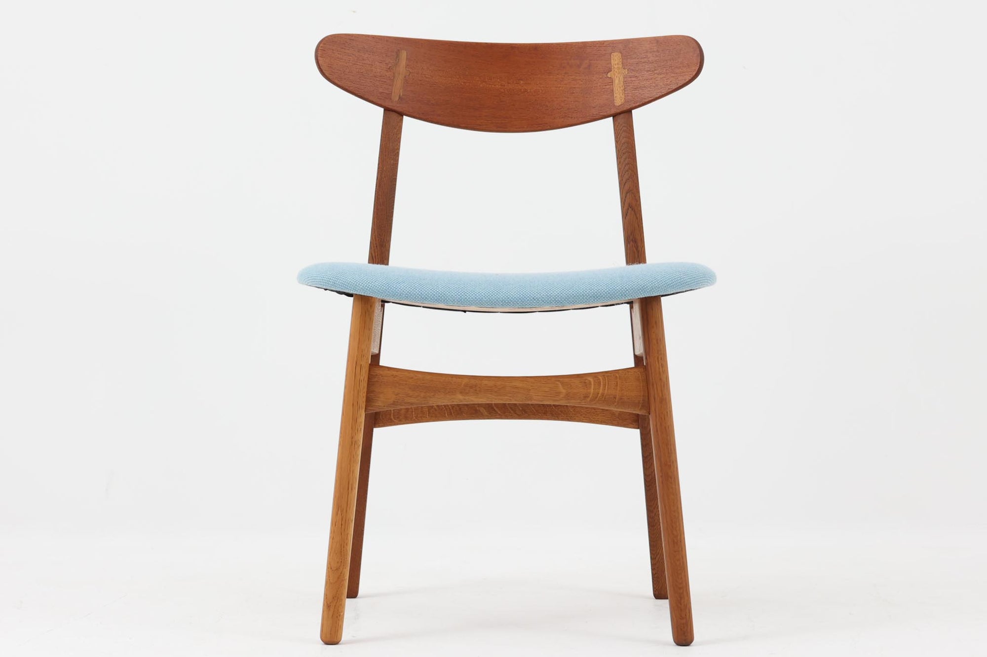 CH30は、ハンス・J・ウェグナーがデザインし、Carl Hansen & Son社によって製造された名作ダイニングチェア。チーク材とオーク材を組み合わせた美しいコントラストが特徴で、木の温もりと洗練されたフォルムが魅力です。特に背もたれと後ろ脚の繋ぎ目は、そのデザインの特徴となっており、独自性とクラフトマンシップの見本と言えるでしょう。背もたれにチーク材が使用された希少なモデルです。人気のため現在復刻されましたが、チーク材とオーク材の組み合わせはビンテージ品でのみ入手可能です。