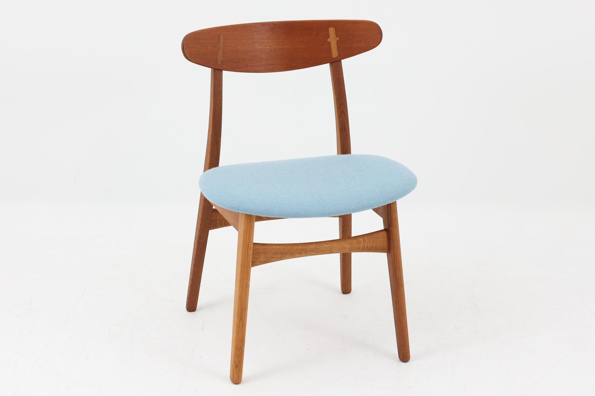 CH30は、ハンス・J・ウェグナーがデザインし、Carl Hansen &amp; Son社によって製造された名作ダイニングチェア。チーク材とオーク材を組み合わせた美しいコントラストが特徴で、木の温もりと洗練されたフォルムが魅力です。特に背もたれと後ろ脚の繋ぎ目は、そのデザインの特徴となっており、独自性とクラフトマンシップの見本と言えるでしょう。背もたれにチーク材が使用された希少なモデルです。人気のため現在復刻されましたが、チーク材とオーク材の組み合わせはビンテージ品でのみ入手可能です。