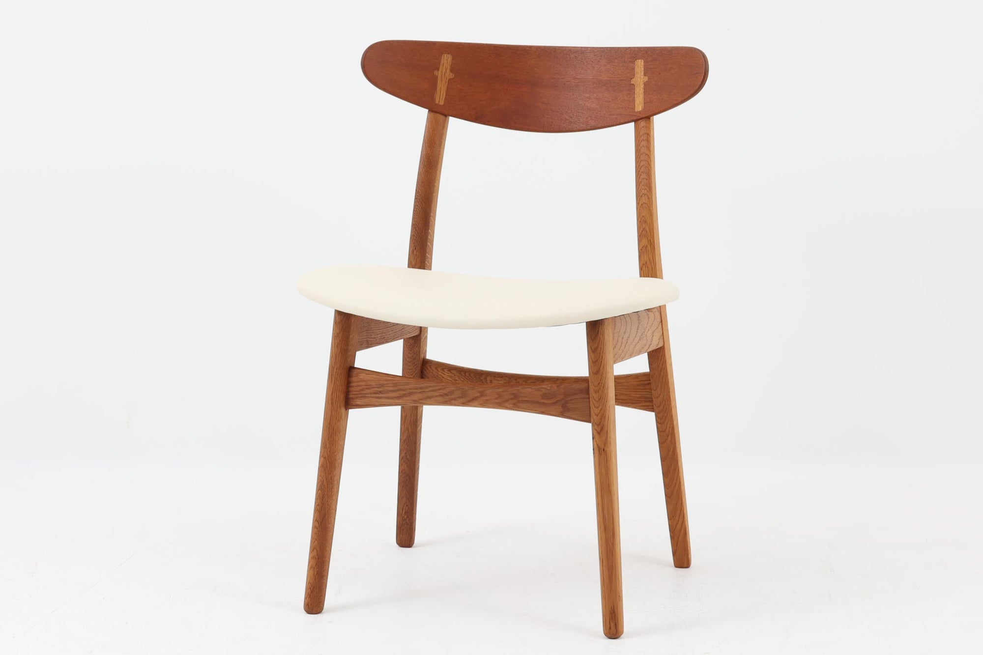CH30は、ハンス・J・ウェグナーがデザインし、Carl Hansen & Son社によって製造された名作ダイニングチェア。チーク材とオーク材を組み合わせた美しいコントラストが特徴で、木の温もりと洗練されたフォルムが魅力です。特に背もたれと後ろ脚の繋ぎ目は、そのデザインの特徴となっており、独自性とクラフトマンシップの見本と言えるでしょう。背もたれにチーク材が使用された希少なモデルです。人気のため現在復刻されましたが、チーク材とオーク材の組み合わせはビンテージ品でのみ入手可能です。