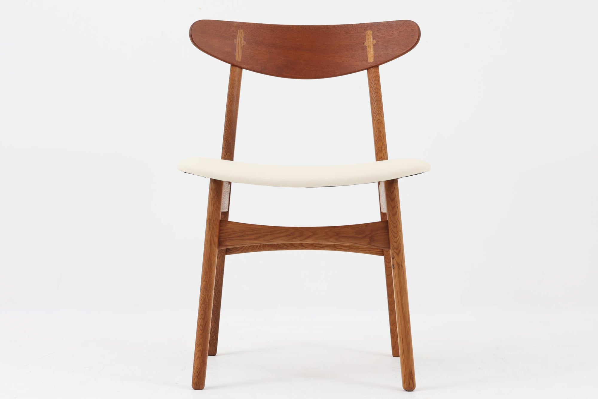 CH30は、ハンス・J・ウェグナーがデザインし、Carl Hansen & Son社によって製造された名作ダイニングチェア。チーク材とオーク材を組み合わせた美しいコントラストが特徴で、木の温もりと洗練されたフォルムが魅力です。特に背もたれと後ろ脚の繋ぎ目は、そのデザインの特徴となっており、独自性とクラフトマンシップの見本と言えるでしょう。背もたれにチーク材が使用された希少なモデルです。人気のため現在復刻されましたが、チーク材とオーク材の組み合わせはビンテージ品でのみ入手可能です。