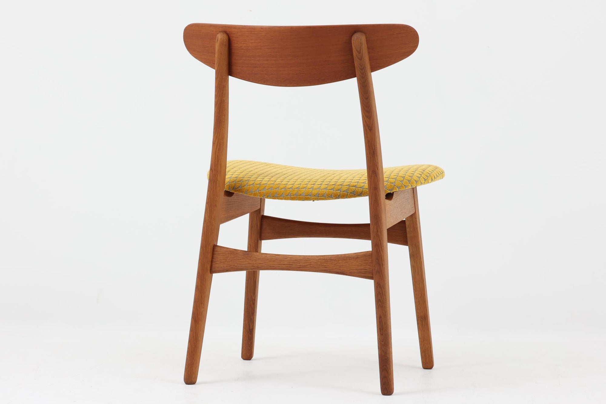 CH30は、ハンス・J・ウェグナーがデザインし、Carl Hansen &amp; Son社によって製造された名作ダイニングチェア。チーク材とオーク材を組み合わせた美しいコントラストが特徴で、木の温もりと洗練されたフォルムが魅力です。特に背もたれと後ろ脚の繋ぎ目は、そのデザインの特徴となっており、独自性とクラフトマンシップの見本と言えるでしょう。背もたれにチーク材が使用された希少なモデルです。人気のため現在復刻されましたが、チーク材とオーク材の組み合わせはビンテージ品でのみ入手可能です。