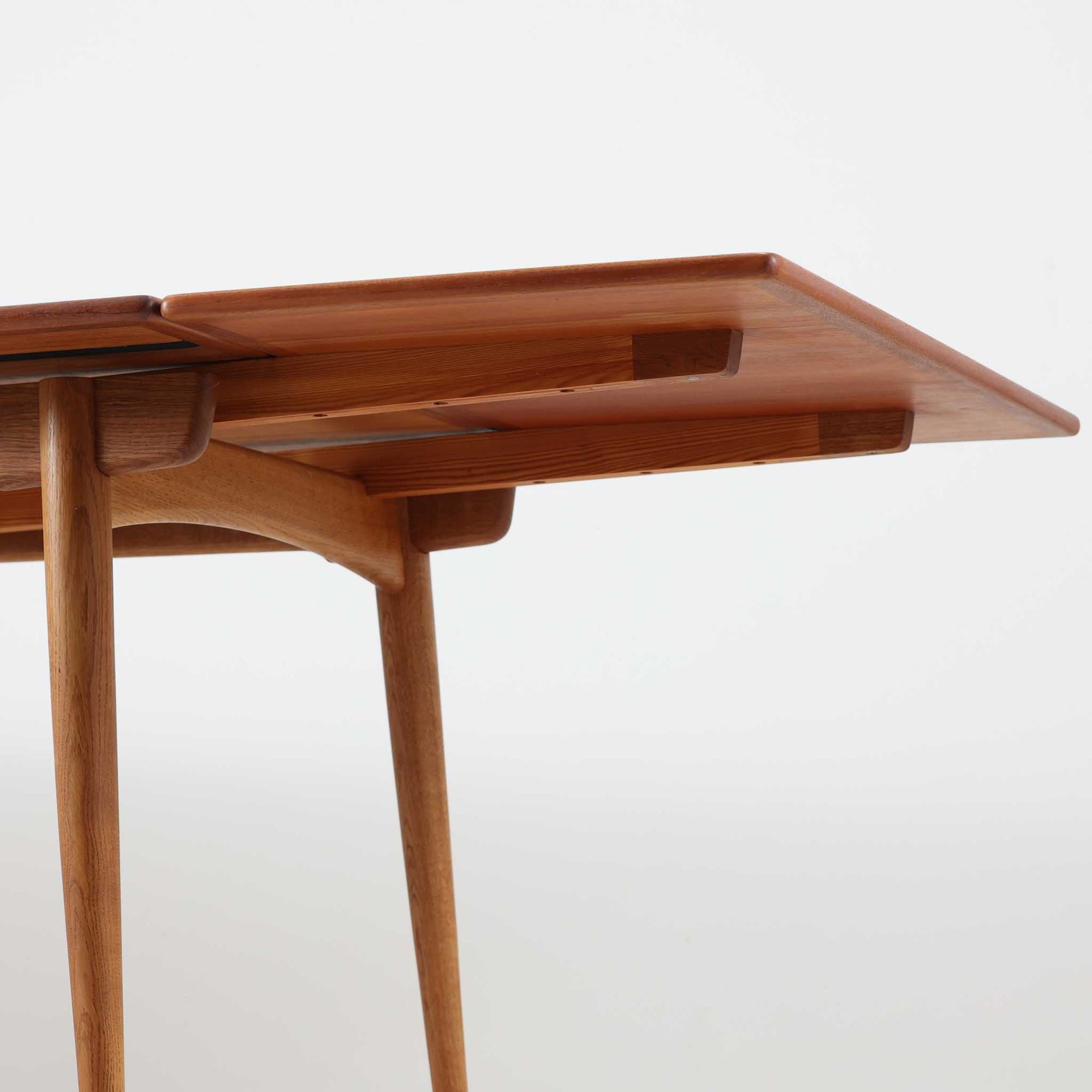 Hans J. Wegnerがデザインを手がけ、Andreas Tuck社から発表されたエクステンションダイニングテーブル「AT312」は、チークとオークのコントラストが美しい北欧ビンテージの名作です。幅140cmから240cmまで拡張可能な機能的な構造により、日常使いから来客時まで柔軟に対応します。緩やかにテーパーした脚部や天板縁の繊細な面取りなど、細部にまでウェグナーの美意識が息づいており、使い込むほどに味わいを深める逸品です。