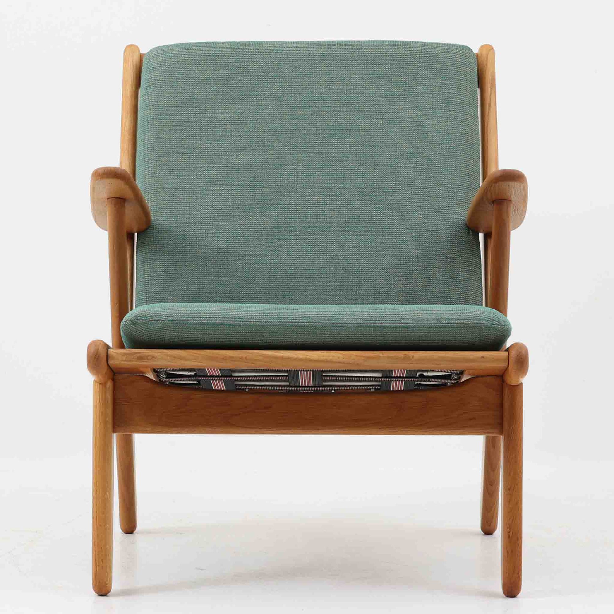 デンマークの国民的ブランドFDBによるビンテージのイージーチェア「J53」。デザイナーは北欧モダンデザインの旗手、Poul M. Volther（ポール・M・ヴォルター）。J53は同氏が手掛けたJシリーズの中でも希少なラウンジチェアタイプで、ゆったりとした座り心地とシンプルな構造美が魅力です。フレームには美しい木目を持つオーク材が使用されており、ナチュラルな風合いが北欧らしい温もりを感じさせます。背面の縦格子デザインや、柔らかくカーブしたアームの形状にも同氏ならではのディテールが感じられます。クッションは新たに張り替え済みで、清潔感のあるグレー系のファブリックが品のある印象を与えます。座面裏FDBのロゴがございます。