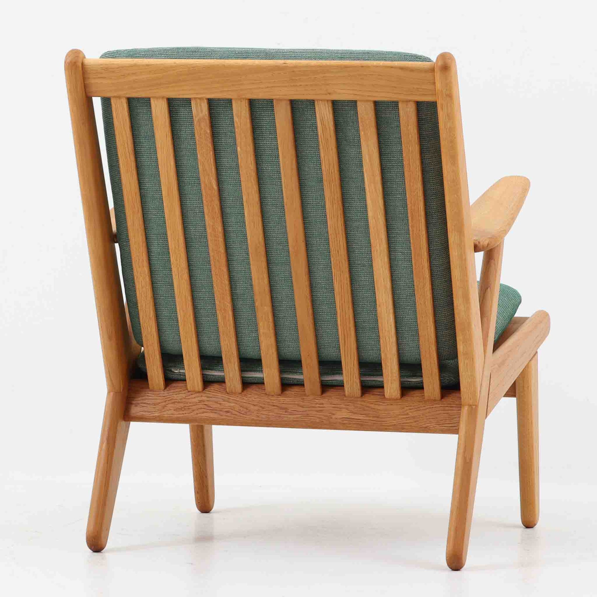 デンマークの国民的ブランドFDBによるビンテージのイージーチェア「J53」。デザイナーは北欧モダンデザインの旗手、Poul M. Volther（ポール・M・ヴォルター）。J53は同氏が手掛けたJシリーズの中でも希少なラウンジチェアタイプで、ゆったりとした座り心地とシンプルな構造美が魅力です。フレームには美しい木目を持つオーク材が使用されており、ナチュラルな風合いが北欧らしい温もりを感じさせます。背面の縦格子デザインや、柔らかくカーブしたアームの形状にも同氏ならではのディテールが感じられます。クッションは新たに張り替え済みで、清潔感のあるグレー系のファブリックが品のある印象を与えます。座面裏FDBのロゴがございます。