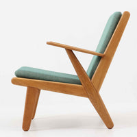 デンマークの国民的ブランドFDBによるビンテージのイージーチェア「J53」。デザイナーは北欧モダンデザインの旗手、Poul M. Volther（ポール・M・ヴォルター）。J53は同氏が手掛けたJシリーズの中でも希少なラウンジチェアタイプで、ゆったりとした座り心地とシンプルな構造美が魅力です。フレームには美しい木目を持つオーク材が使用されており、ナチュラルな風合いが北欧らしい温もりを感じさせます。背面の縦格子デザインや、柔らかくカーブしたアームの形状にも同氏ならではのディテールが感じられます。クッションは新たに張り替え済みで、清潔感のあるグレー系のファブリックが品のある印象を与えます。座面裏FDBのロゴがございます。