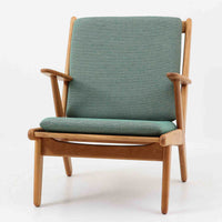 デンマークの国民的ブランドFDBによるビンテージのイージーチェア「J53」。デザイナーは北欧モダンデザインの旗手、Poul M. Volther（ポール・M・ヴォルター）。J53は同氏が手掛けたJシリーズの中でも希少なラウンジチェアタイプで、ゆったりとした座り心地とシンプルな構造美が魅力です。フレームには美しい木目を持つオーク材が使用されており、ナチュラルな風合いが北欧らしい温もりを感じさせます。背面の縦格子デザインや、柔らかくカーブしたアームの形状にも同氏ならではのディテールが感じられます。クッションは新たに張り替え済みで、清潔感のあるグレー系のファブリックが品のある印象を与えます。座面裏FDBのロゴがございます。