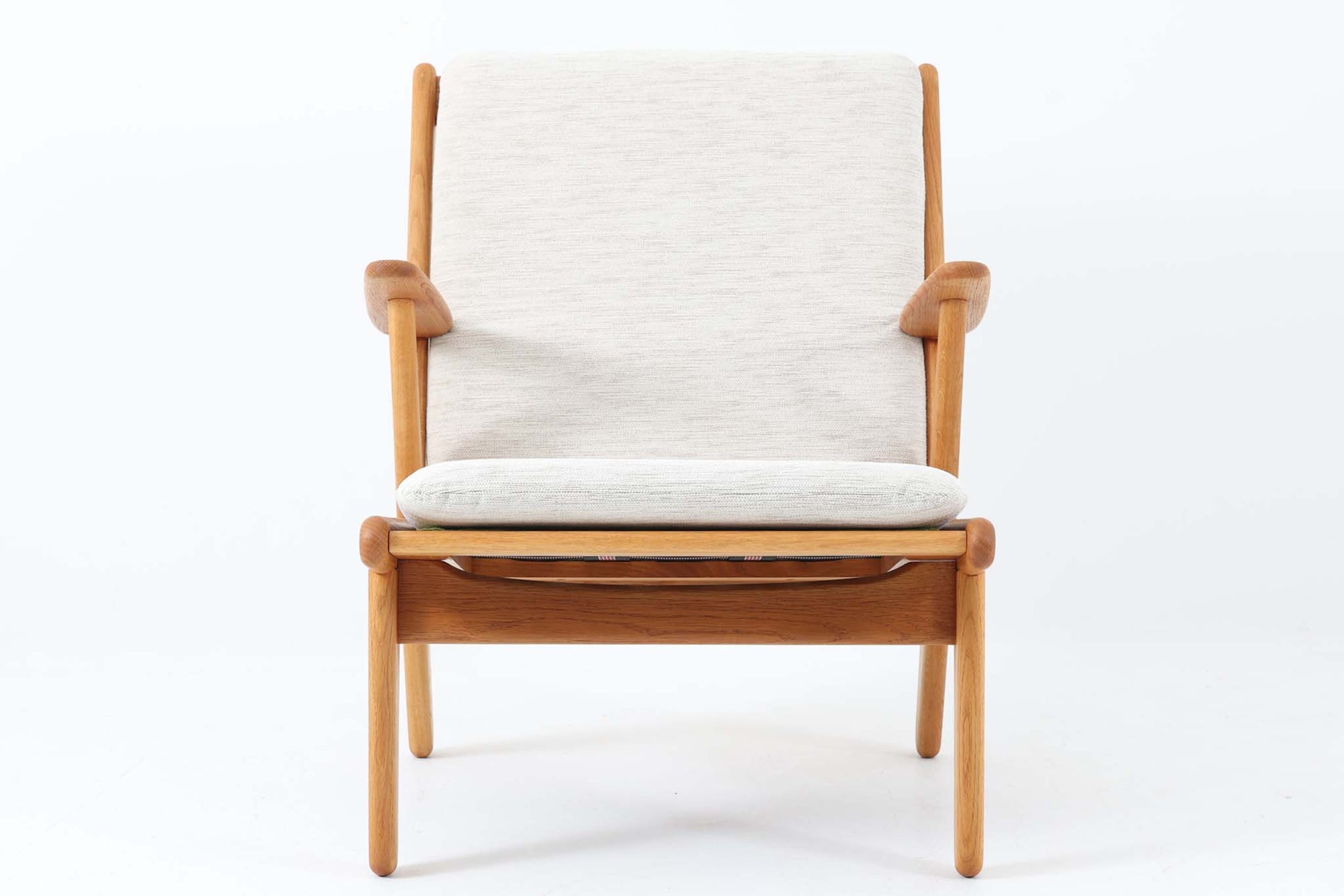 デンマークの国民的ブランドFDBによるビンテージのイージーチェア「J53」。デザイナーは北欧モダンデザインの旗手、Poul m. Volther（ポール・m・ヴォルター）。J53は同氏が手掛けたJシリーズの中でも希少なラウンジチェアタイプで、ゆったりとした座り心地とシンプルな構造美が魅力です。フレームには美しい木目を持つオーク材が使用されており、ナチュラルな風合いが北欧らしい温もりを感じさせます。背面の縦格子デザインや、柔らかくカーブしたアームの形状にも同氏ならではのディテールが感じられます。クッションは新たに張り替え済みで、清潔感のあるアイボリー系のファブリックが品のある印象を与えます。背面に「mADE IN DENmARK」およびFDBの刻印あり。