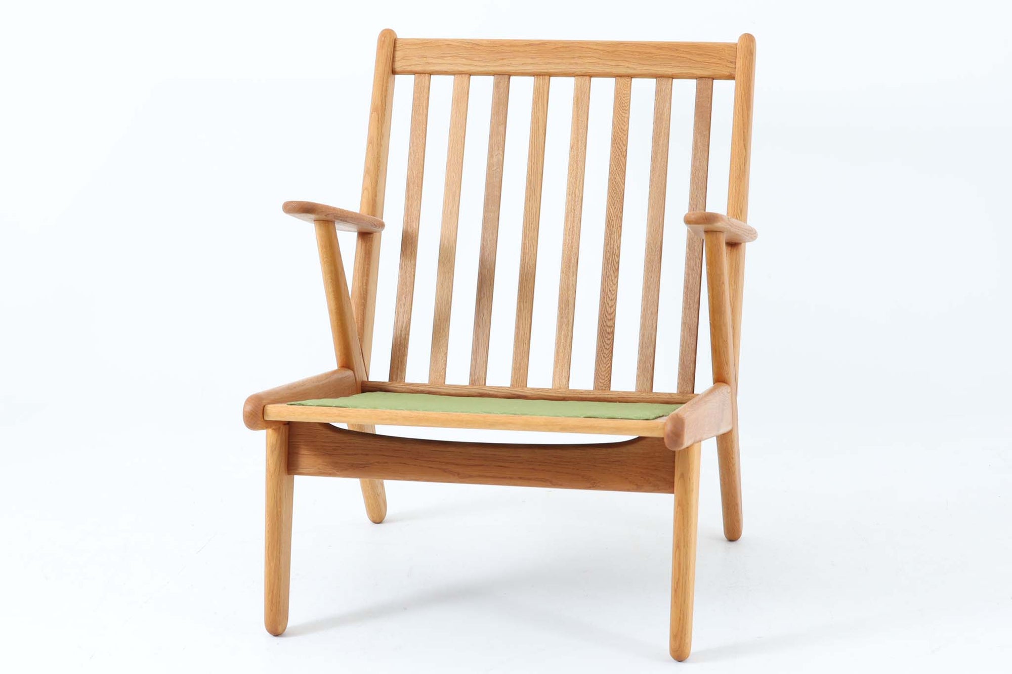 デンマークの国民的ブランドFDBによるビンテージのイージーチェア「J53」。デザイナーは北欧モダンデザインの旗手、Poul m. Volther（ポール・m・ヴォルター）。J53は同氏が手掛けたJシリーズの中でも希少なラウンジチェアタイプで、ゆったりとした座り心地とシンプルな構造美が魅力です。フレームには美しい木目を持つオーク材が使用されており、ナチュラルな風合いが北欧らしい温もりを感じさせます。背面の縦格子デザインや、柔らかくカーブしたアームの形状にも同氏ならではのディテールが感じられます。クッションは新たに張り替え済みで、清潔感のあるアイボリー系のファブリックが品のある印象を与えます。背面に「mADE IN DENmARK」およびFDBの刻印あり。