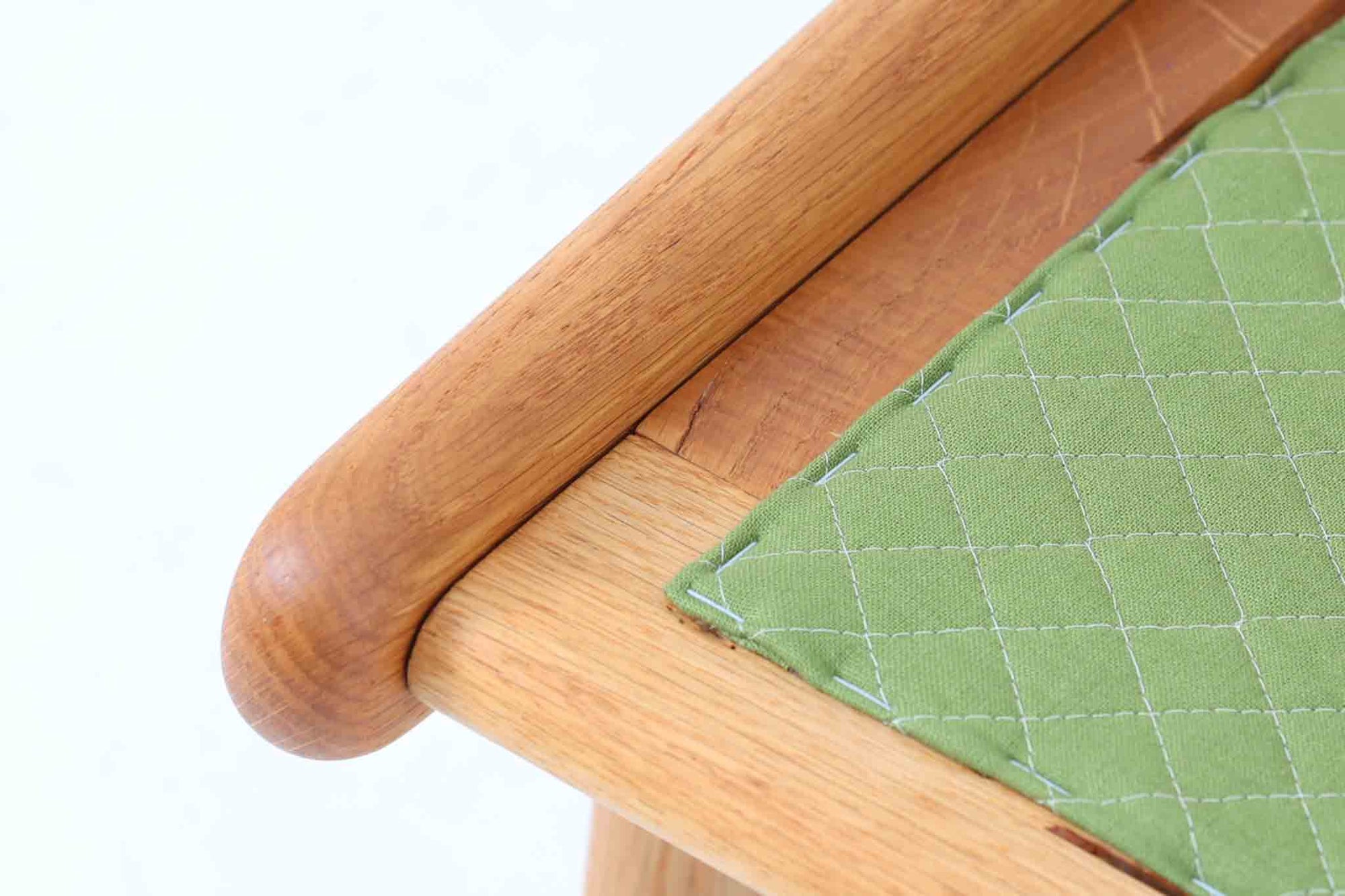 デンマークの国民的ブランドFDBによるビンテージのイージーチェア「J53」。デザイナーは北欧モダンデザインの旗手、Poul m. Volther（ポール・m・ヴォルター）。J53は同氏が手掛けたJシリーズの中でも希少なラウンジチェアタイプで、ゆったりとした座り心地とシンプルな構造美が魅力です。フレームには美しい木目を持つオーク材が使用されており、ナチュラルな風合いが北欧らしい温もりを感じさせます。背面の縦格子デザインや、柔らかくカーブしたアームの形状にも同氏ならではのディテールが感じられます。クッションは新たに張り替え済みで、清潔感のあるアイボリー系のファブリックが品のある印象を与えます。背面に「mADE IN DENmARK」およびFDBの刻印あり。