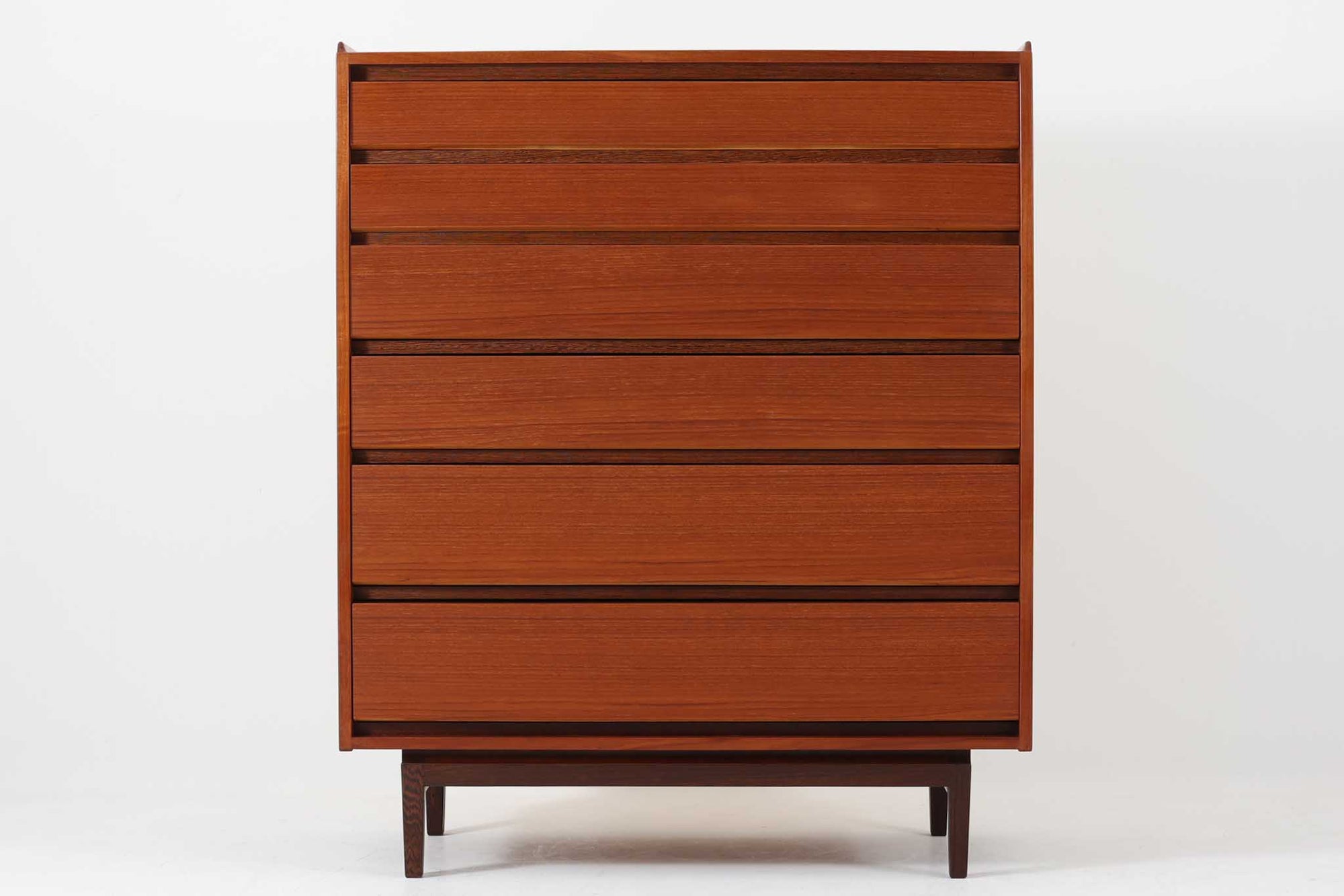 デンマーク製の北欧ビンテージチェストです。本体には上質なチーク材を使用し、引き出し下部と脚部には深みのある色味が魅力のウェンジ材が用いられており、異素材の組み合わせが洗練された印象を与えます。引き出しは合計6段あり、上段2杯には仕切り付きで小物整理にも便利。フラットな引き出し前板と、すっきりとした木脚が北欧らしいミニマルな美しさを際立たせています。シンプルでありながら個性のあるクオリティーの高いデザインは、リビングやベッドルームなど幅広い空間に馴染みます。
