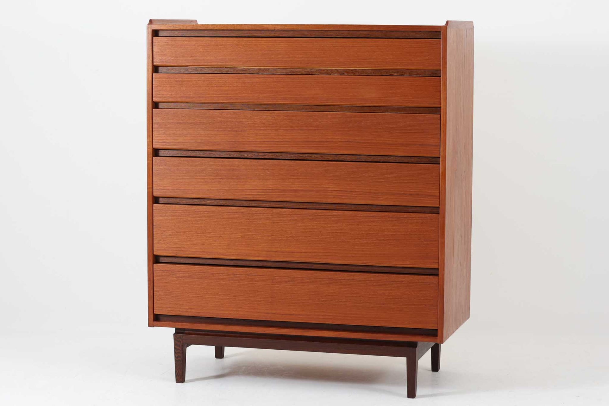 デンマーク製の北欧ビンテージチェストです。本体には上質なチーク材を使用し、引き出し下部と脚部には深みのある色味が魅力のウェンジ材が用いられており、異素材の組み合わせが洗練された印象を与えます。引き出しは合計6段あり、上段2杯には仕切り付きで小物整理にも便利。フラットな引き出し前板と、すっきりとした木脚が北欧らしいミニマルな美しさを際立たせています。シンプルでありながら個性のあるクオリティーの高いデザインは、リビングやベッドルームなど幅広い空間に馴染みます。