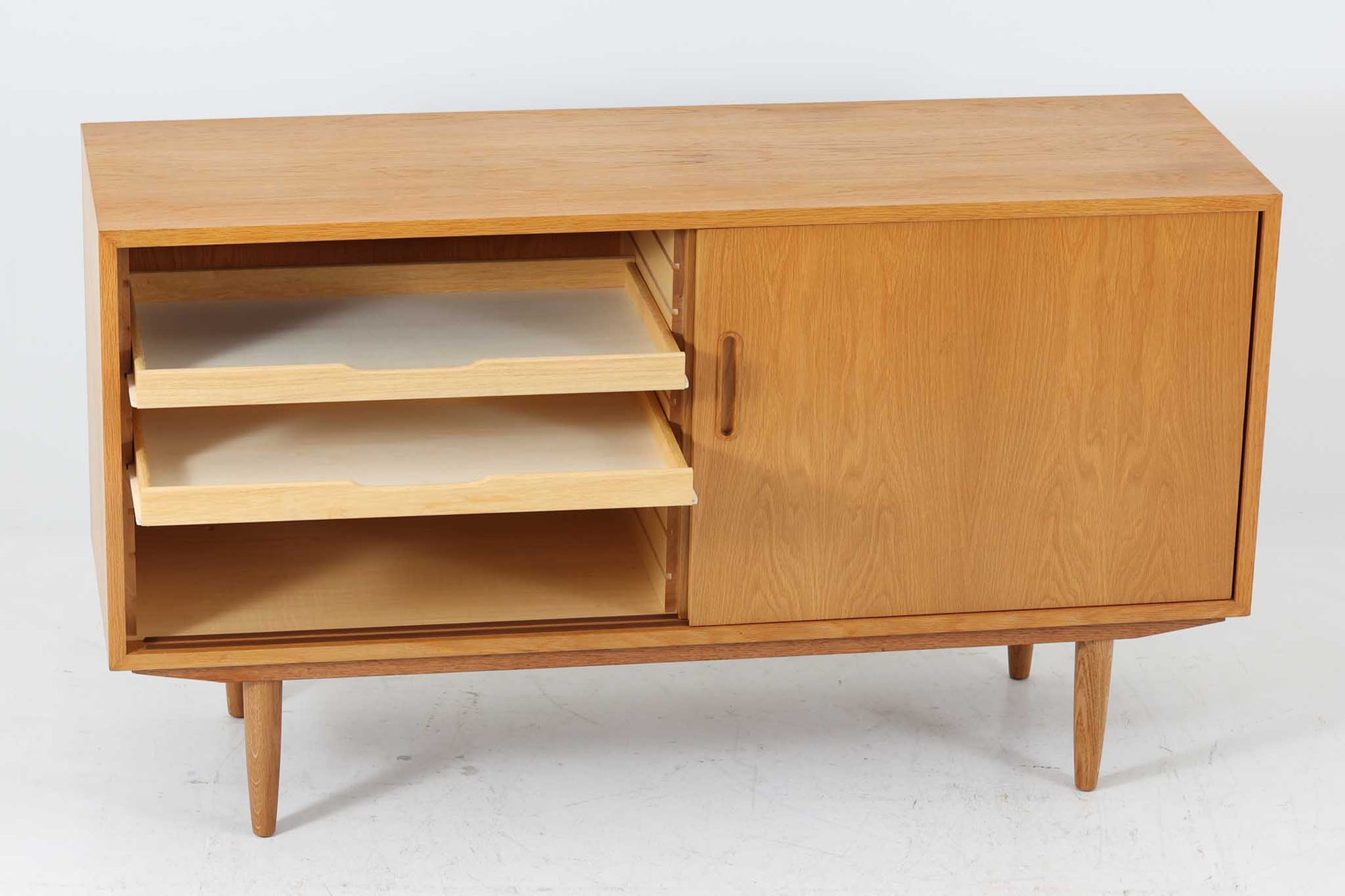 北欧より買い付けたサイドボードです。収納部の右側には、元々レコード収納用として設計されていたと思われる取り外し可能な縦仕切りがあり、幅の調整も可能です。棚板は取り外しできませんが、縦仕切りは全て取り外し可能で、大きなアイテムの収納にも対応できます。左側の収納部には、取り外しや可動が可能な引き出しが2杯備わっており、使い勝手も良好です。シンプルながらも高いクオリティを誇り、デンマークの家具デザイナーPoul Hundevadによってデザインされた本作は、デンマークの厳しい品質基準を満たした「DANISH FURNITUREmAKE'S CONTROL」のロゴシールが付いております。